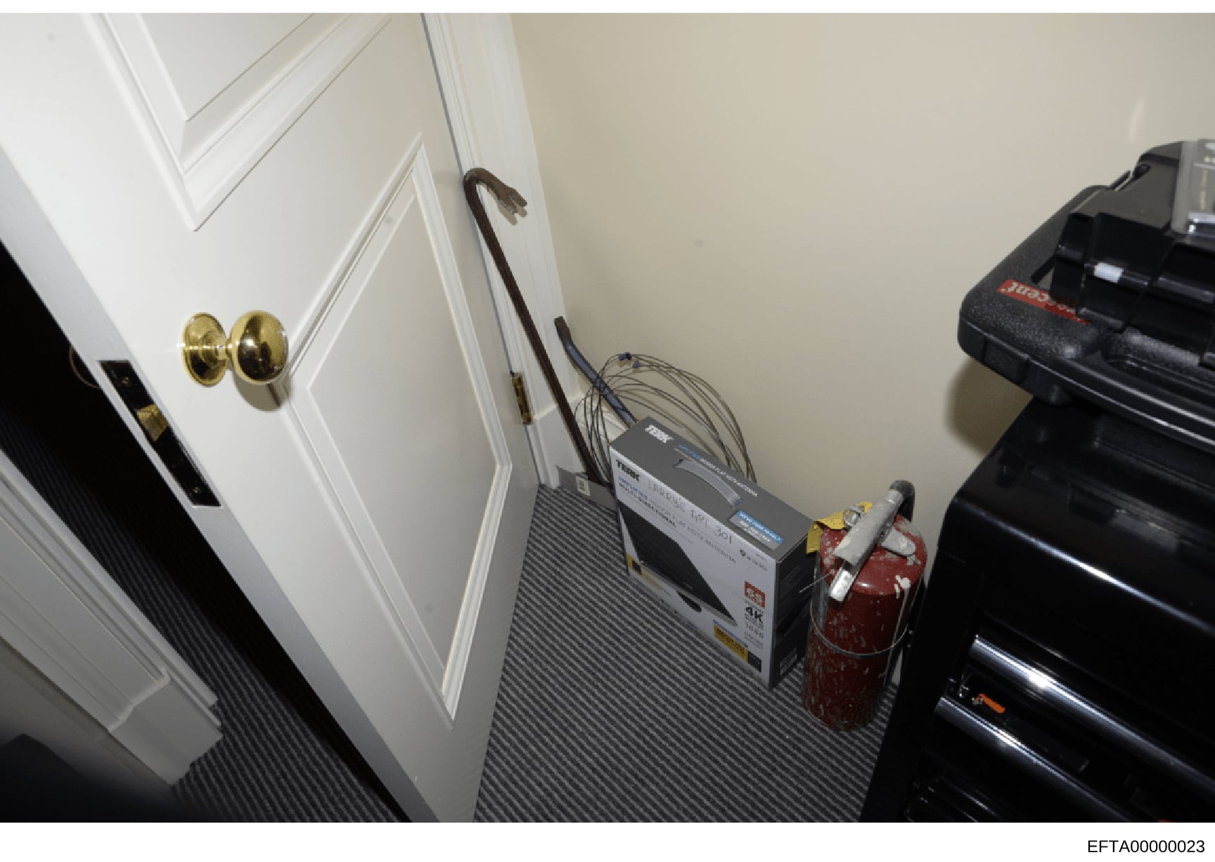 This photograph shows the interior of a closet or utility space, featuring electrical equipment including what appears to be a server or network device with cables, a fire extinguisher, and various household items. The space has white paneled doors w