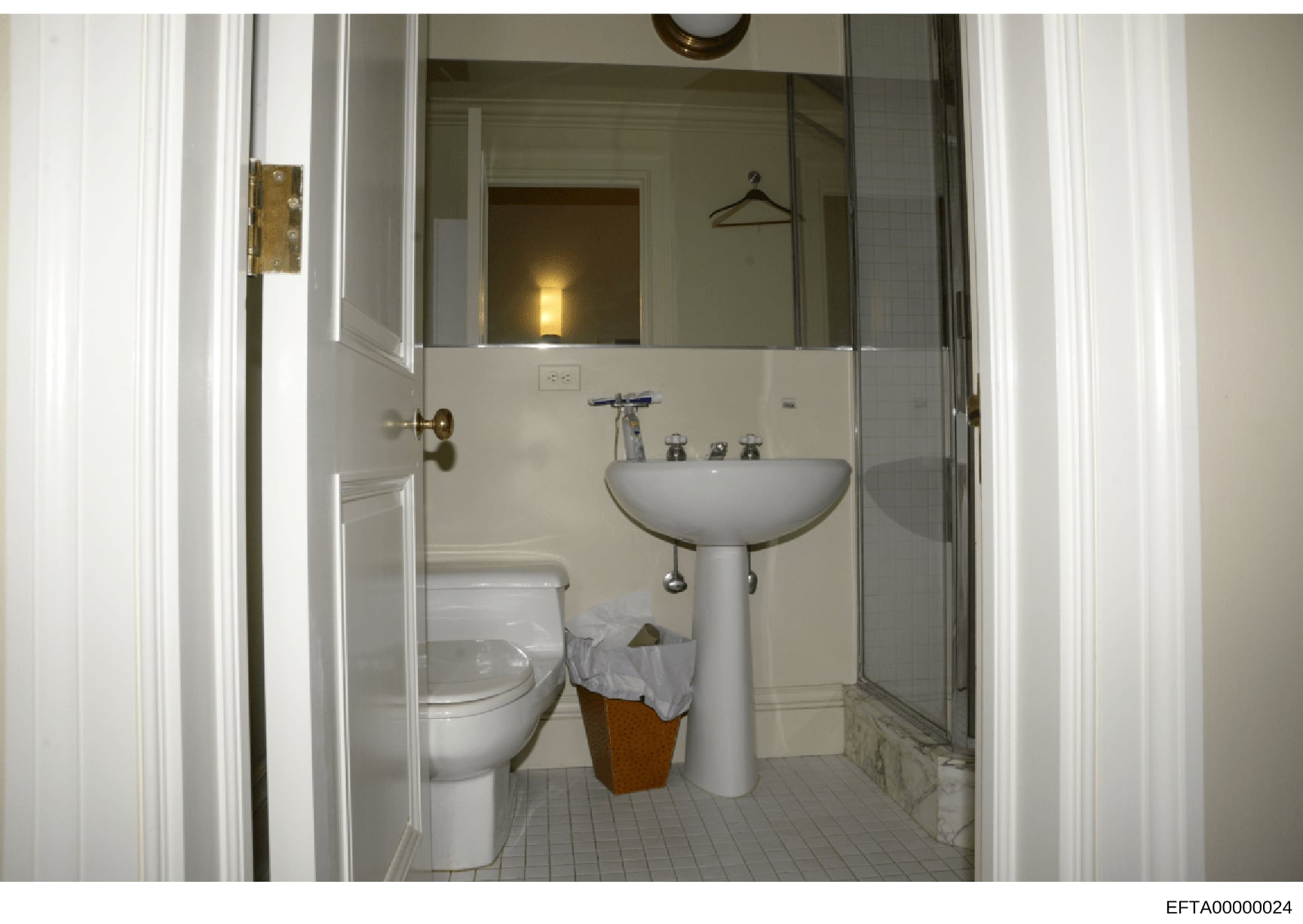 This is a photograph of a bathroom interior, showing standard fixtures including a pedestal sink, toilet, and mirror. The image appears to be part of property documentation, possibly from a residential property inspection or inventory related to the