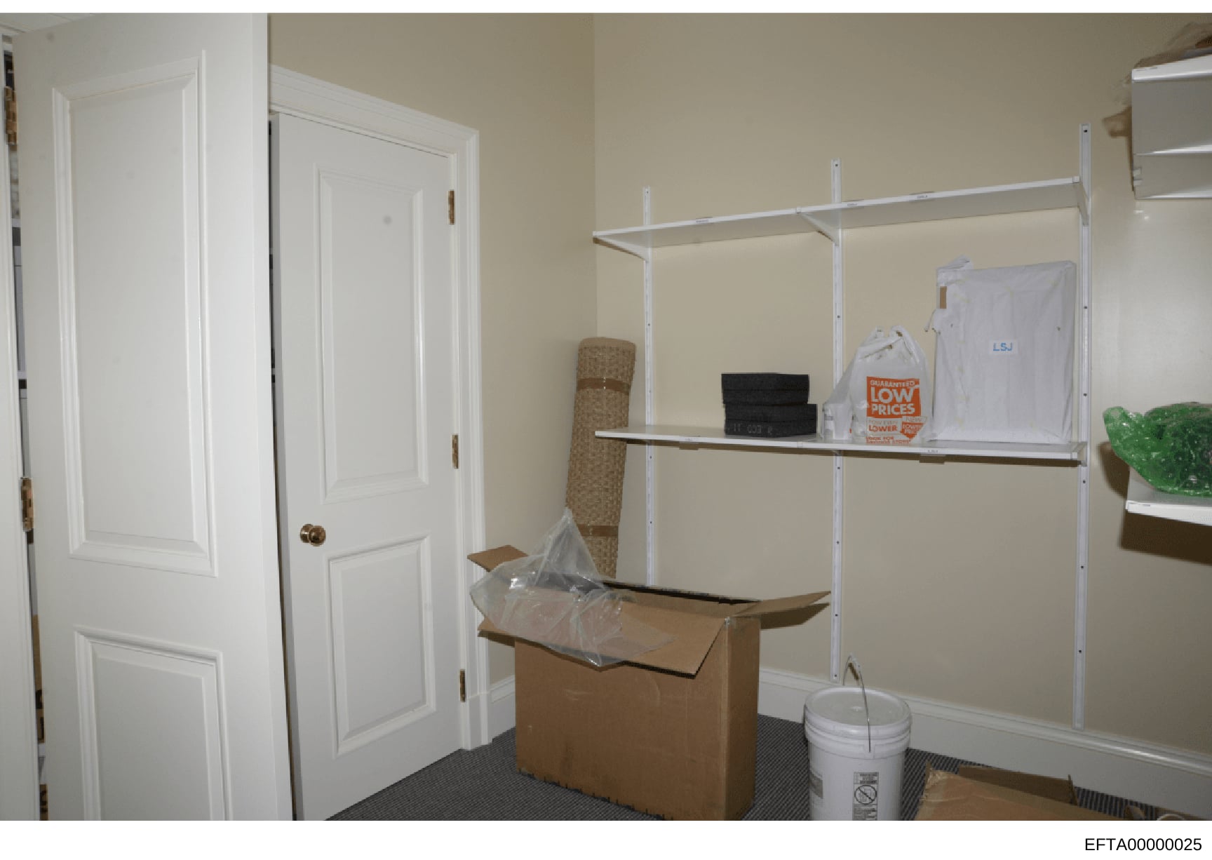 This photograph shows an interior room or storage space containing shelving units, cardboard boxes, and various items. The image appears to be documentary evidence photography, likely taken during an investigation to document property conditions or c