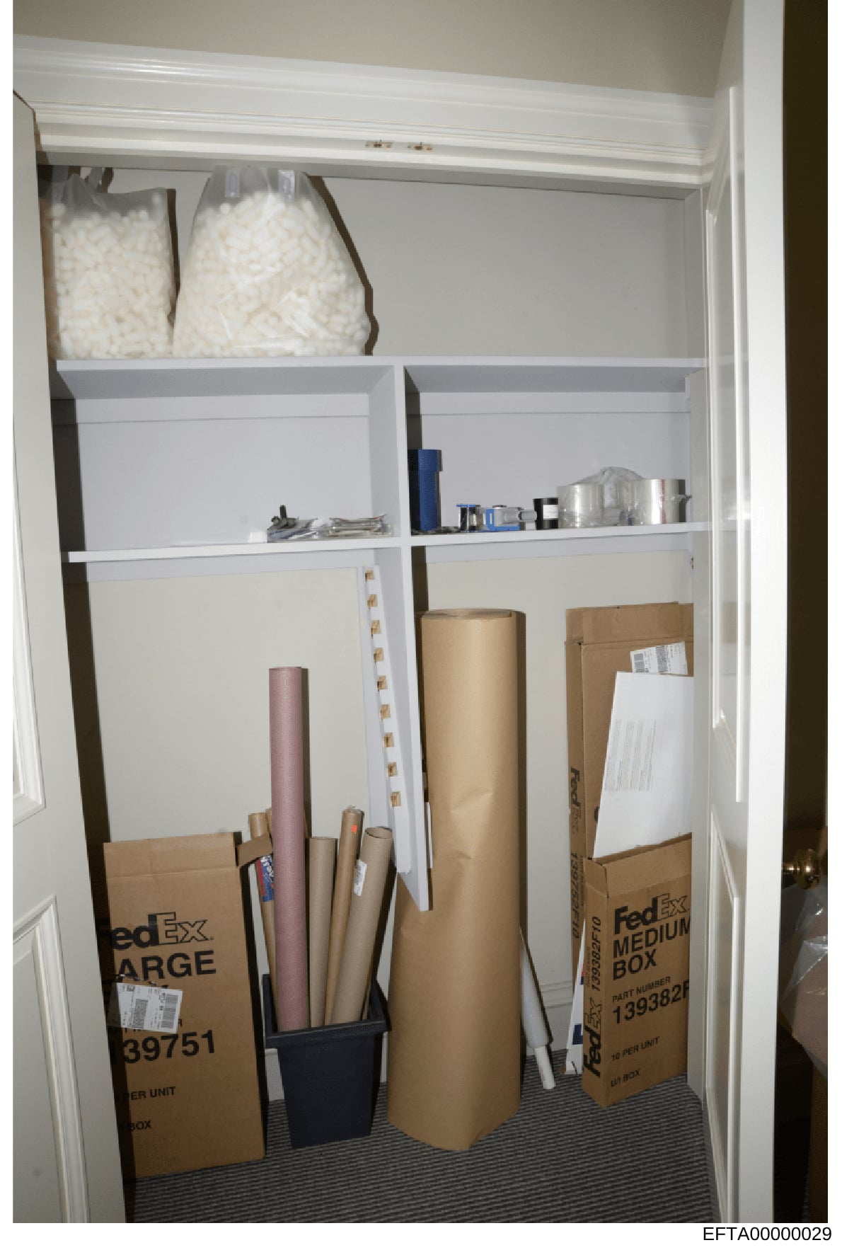 This is a photograph of a closet interior showing various stored items including packing materials, boxes, household supplies, and storage containers. The image appears to be part of evidence documentation, likely taken during a property search or in