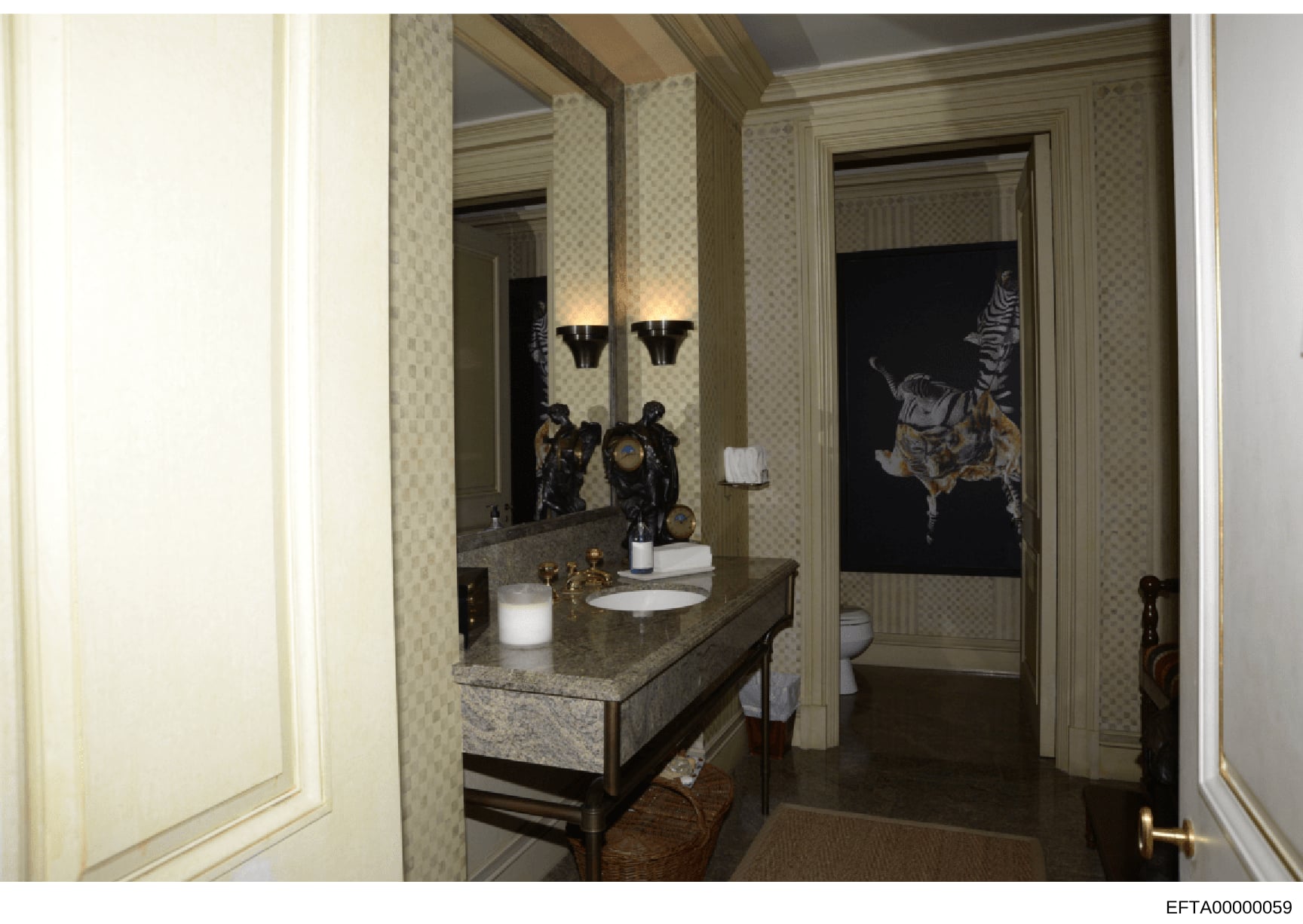This is a photograph of an upscale bathroom interior, likely from one of Jeffrey Epstein's properties. The image shows a sophisticated vanity setup with a granite countertop, dual sinks, large mirrors with wall sconces, decorative black sculptural fi