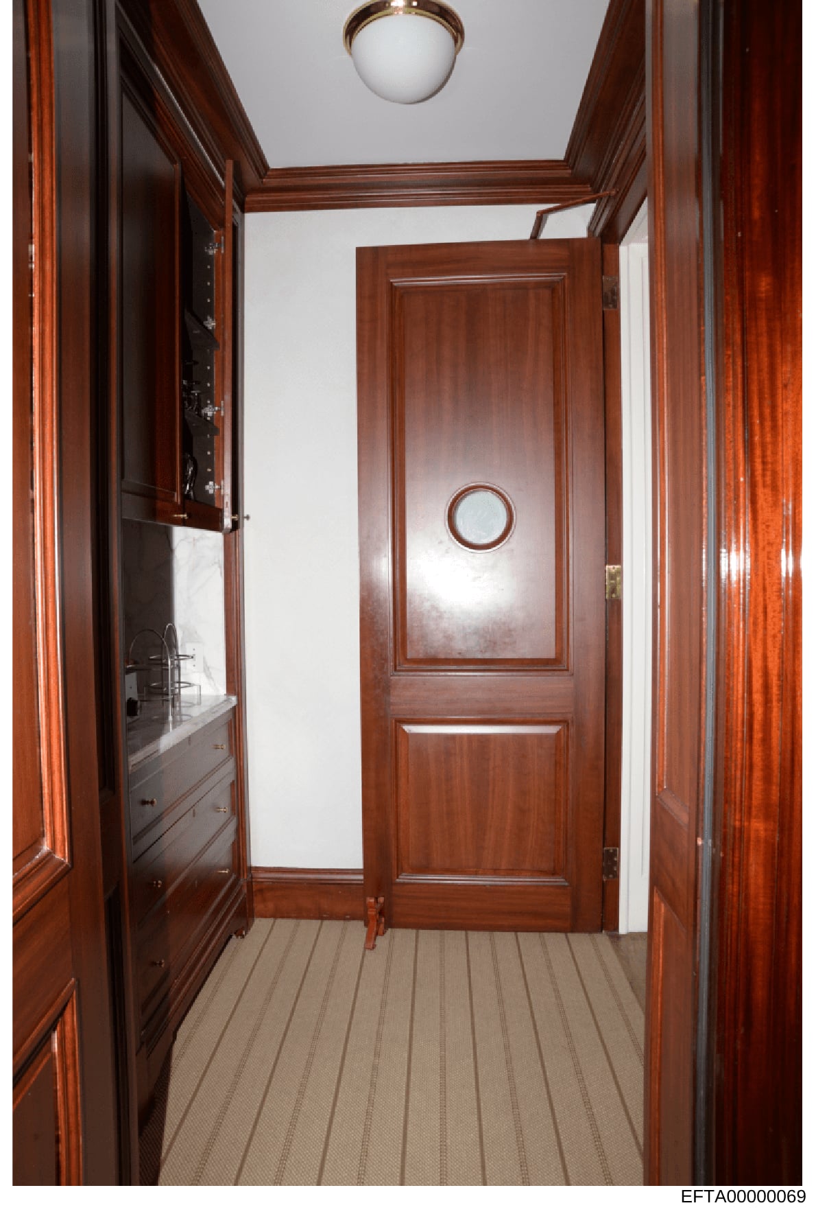 This is a photograph of an interior hallway featuring rich mahogany wood paneling, ornate wooden doors, and built-in cabinetry. The image appears to be from a property documentation or evidence photo collection related to the investigation, showing t