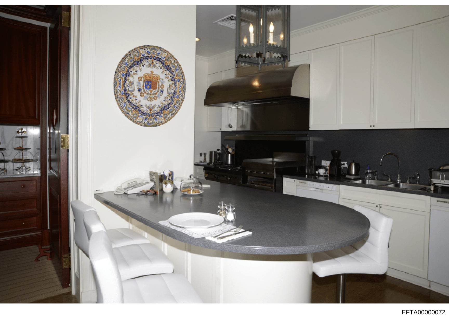 This is a high-resolution photograph of an upscale residential kitchen, likely from one of Jeffrey Epstein's properties. The kitchen features a distinctive oval-shaped island with white base and dark countertop, high-end appliances, custom cabinetry,