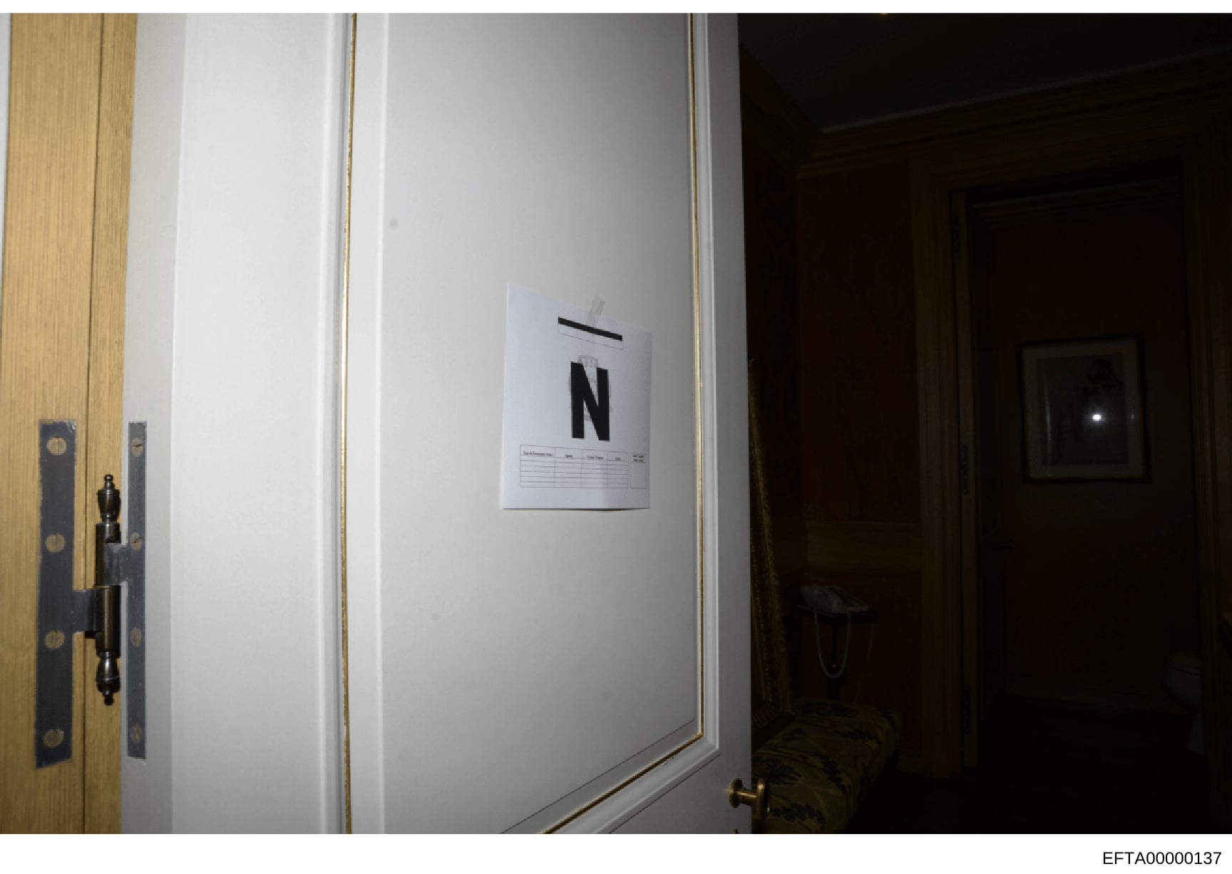 This is an investigative evidence photograph showing an interior doorway marked with an 'N' identification placard, commonly used in law enforcement documentation to identify and catalog rooms or spaces during property searches. The photo appears to 