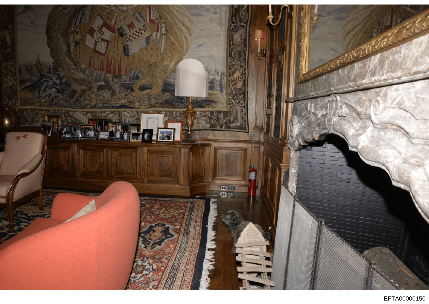 This is a photograph of an elegantly decorated interior room featuring 18th-century style architectural elements, including ornate wall paneling, detailed ceiling murals, gilded frames, and period furniture. The room displays multiple framed photogra