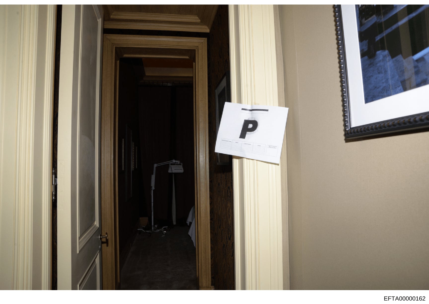 This photograph shows an interior doorway of a residential property with an evidence marker labeled 'P' attached to the door frame. The image appears to be part of a property inspection or law enforcement documentation, likely taken during a search o