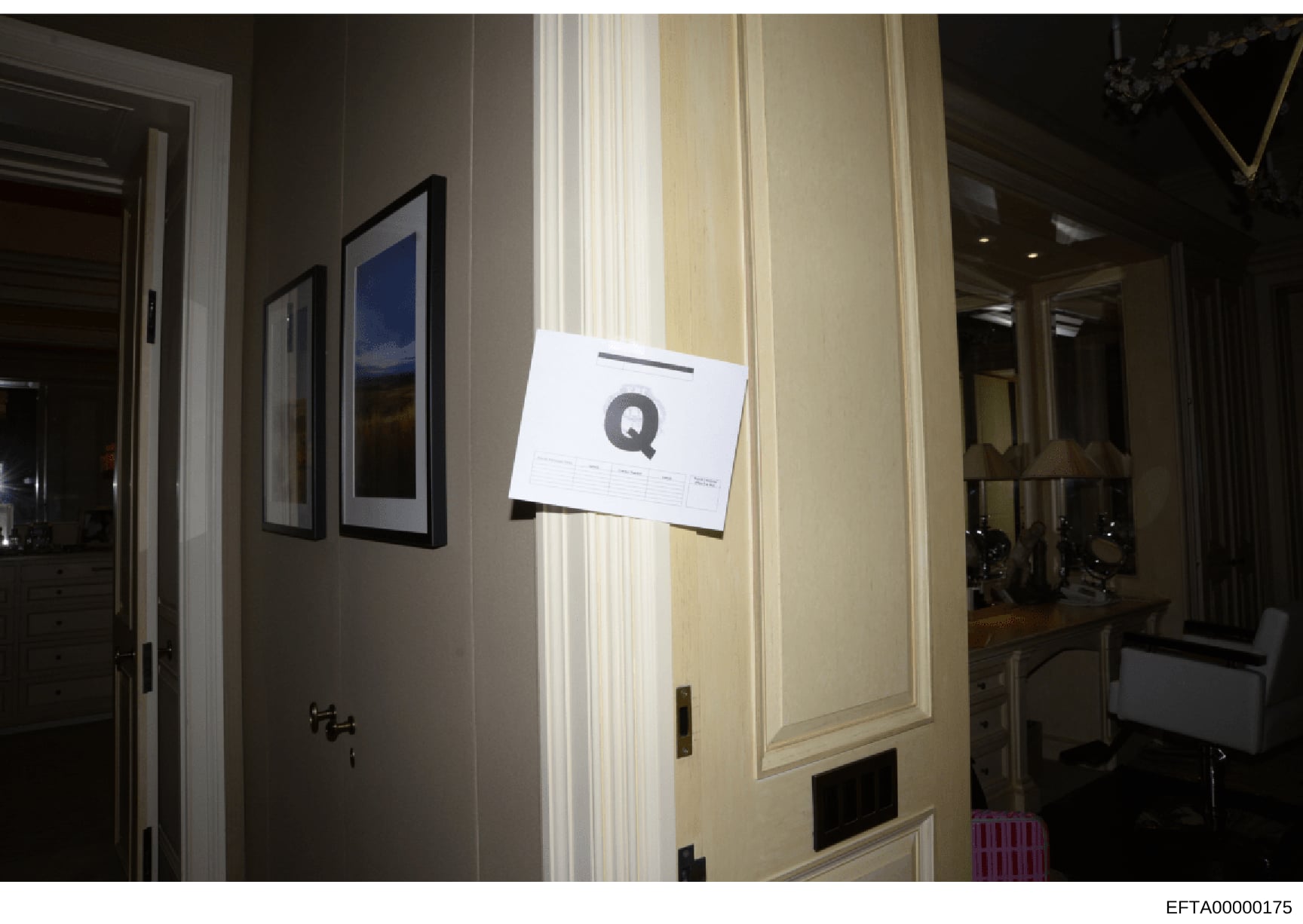 This is an evidence photograph showing the interior of a room with a white evidence marker labeled 'Q' affixed to a wall. The photo documents the location and condition of an item or area of interest during the investigation. The room features contem
