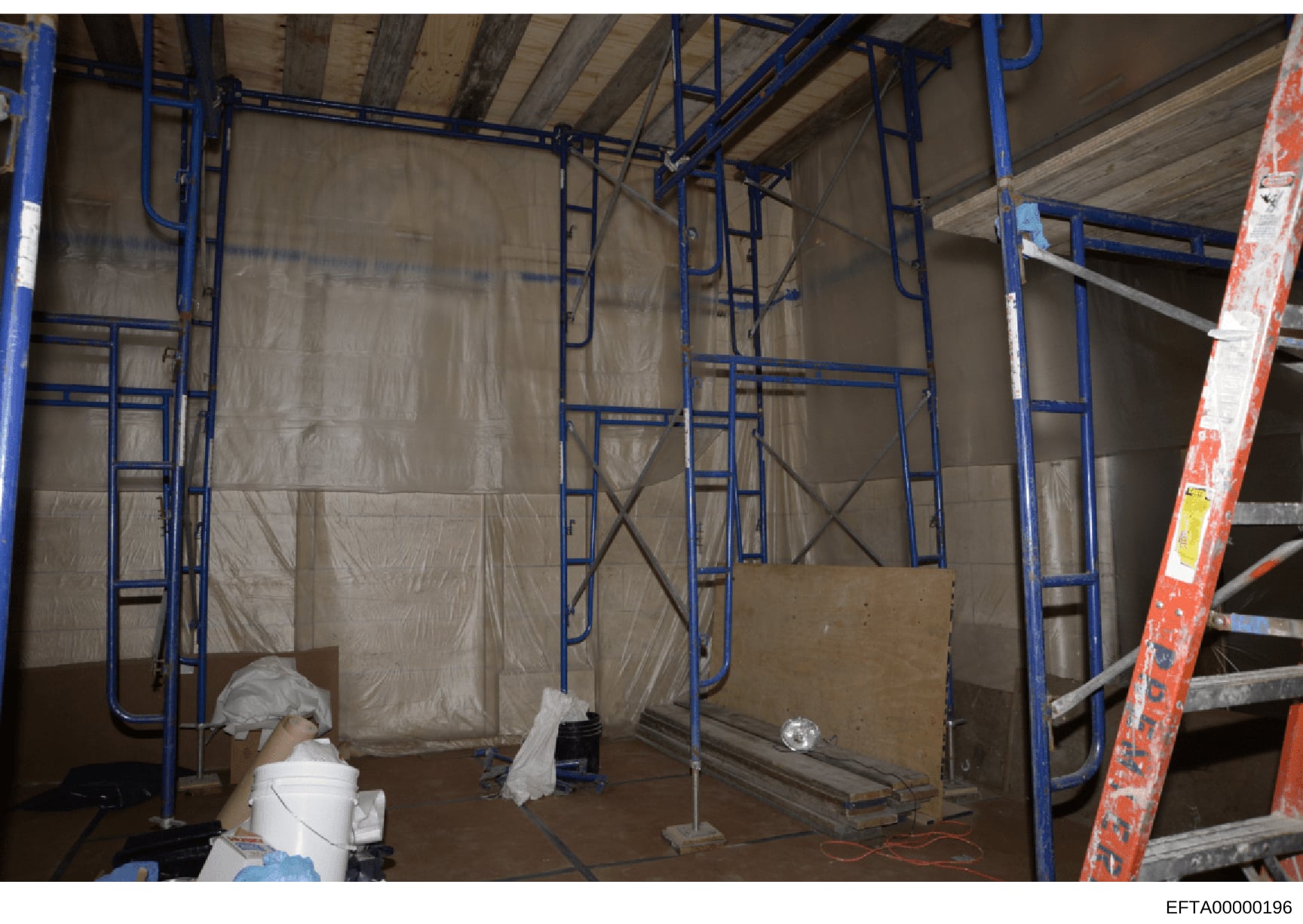 This photograph documents an interior space under construction, showing metal framing, plastic sheeting for dust containment, and construction materials. The image appears to be part of property documentation, possibly related to one of Epstein's pro