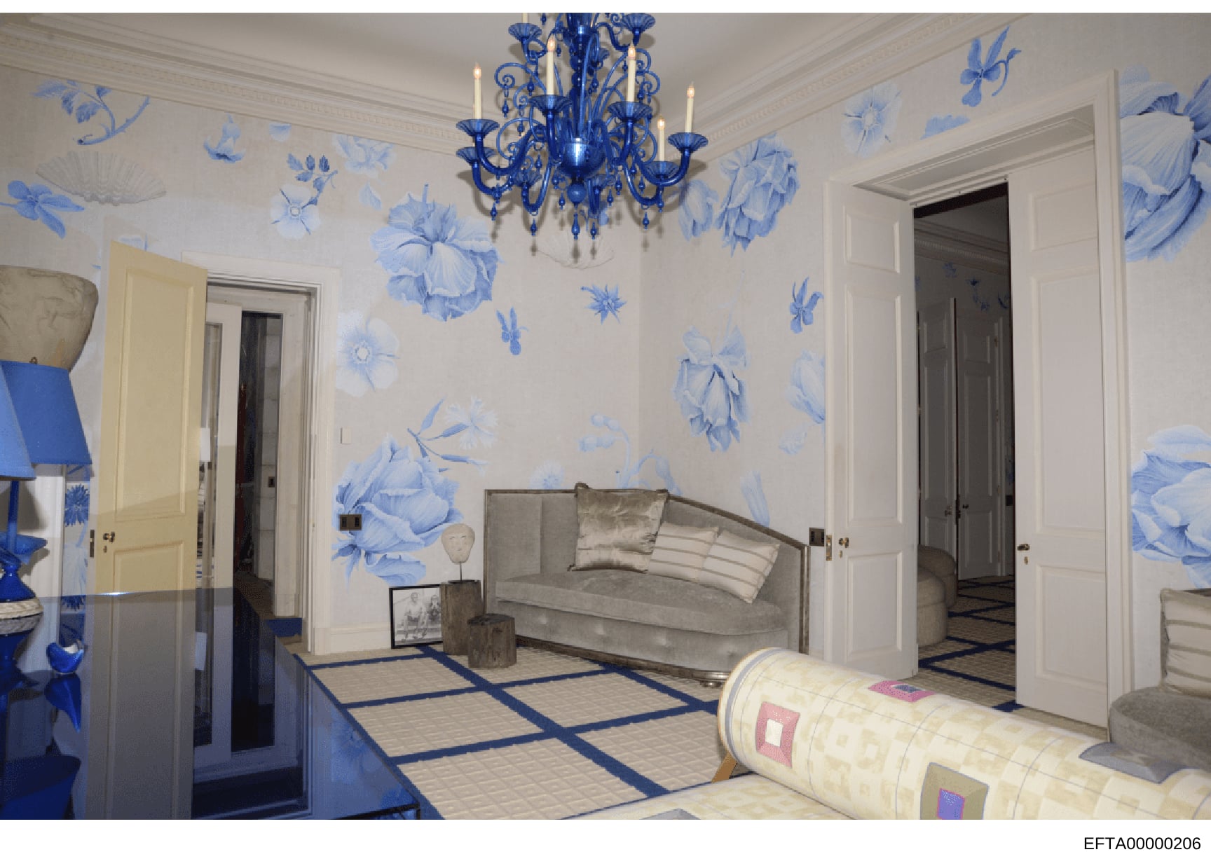 This is an architectural or interior design rendering showing a luxuriously decorated room with blue-and-white botanical wallpaper, ornate blue Murano glass chandelier, gray upholstered seating, geometric patterned flooring, and multiple doorways. Th
