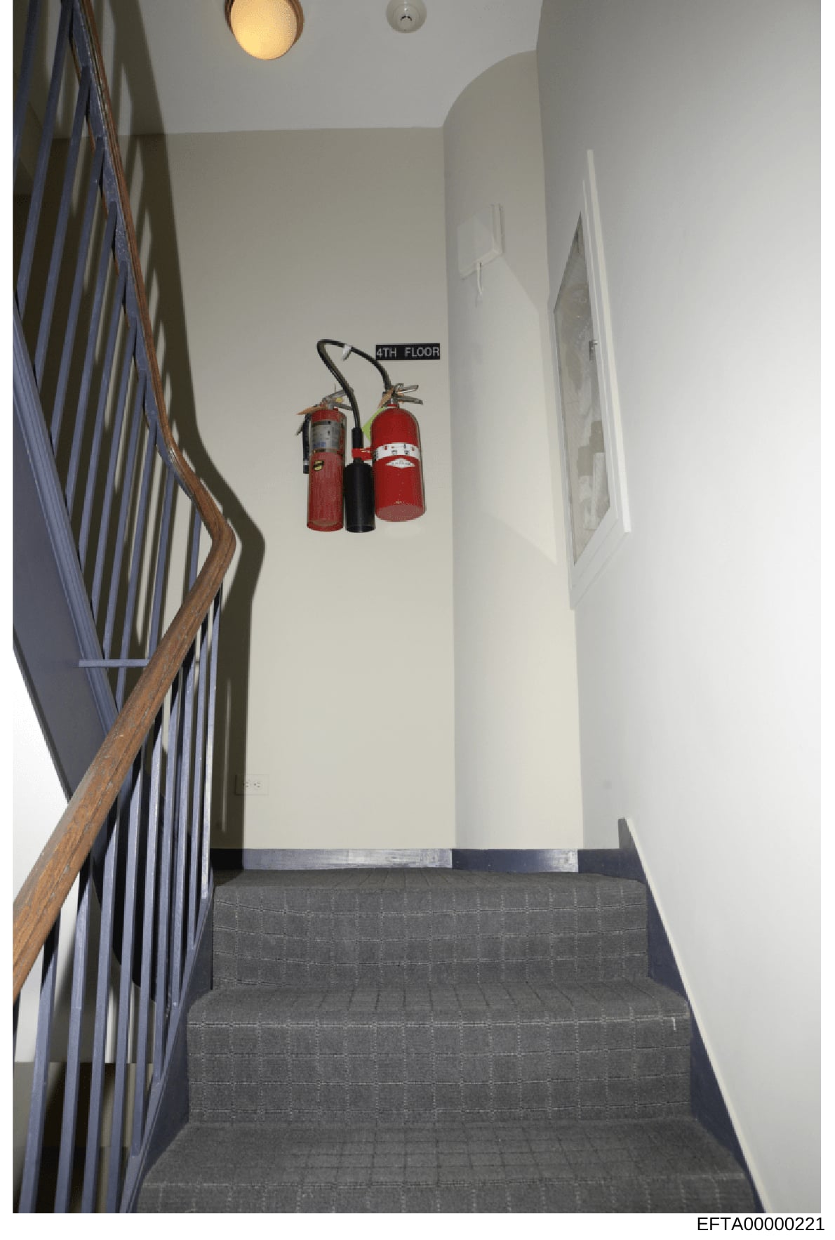 This is a photograph of an interior stairwell showing the fourth floor landing, featuring fire safety equipment mounted on the wall. The image documents the building's fire safety infrastructure and appears to be part of property documentation relate