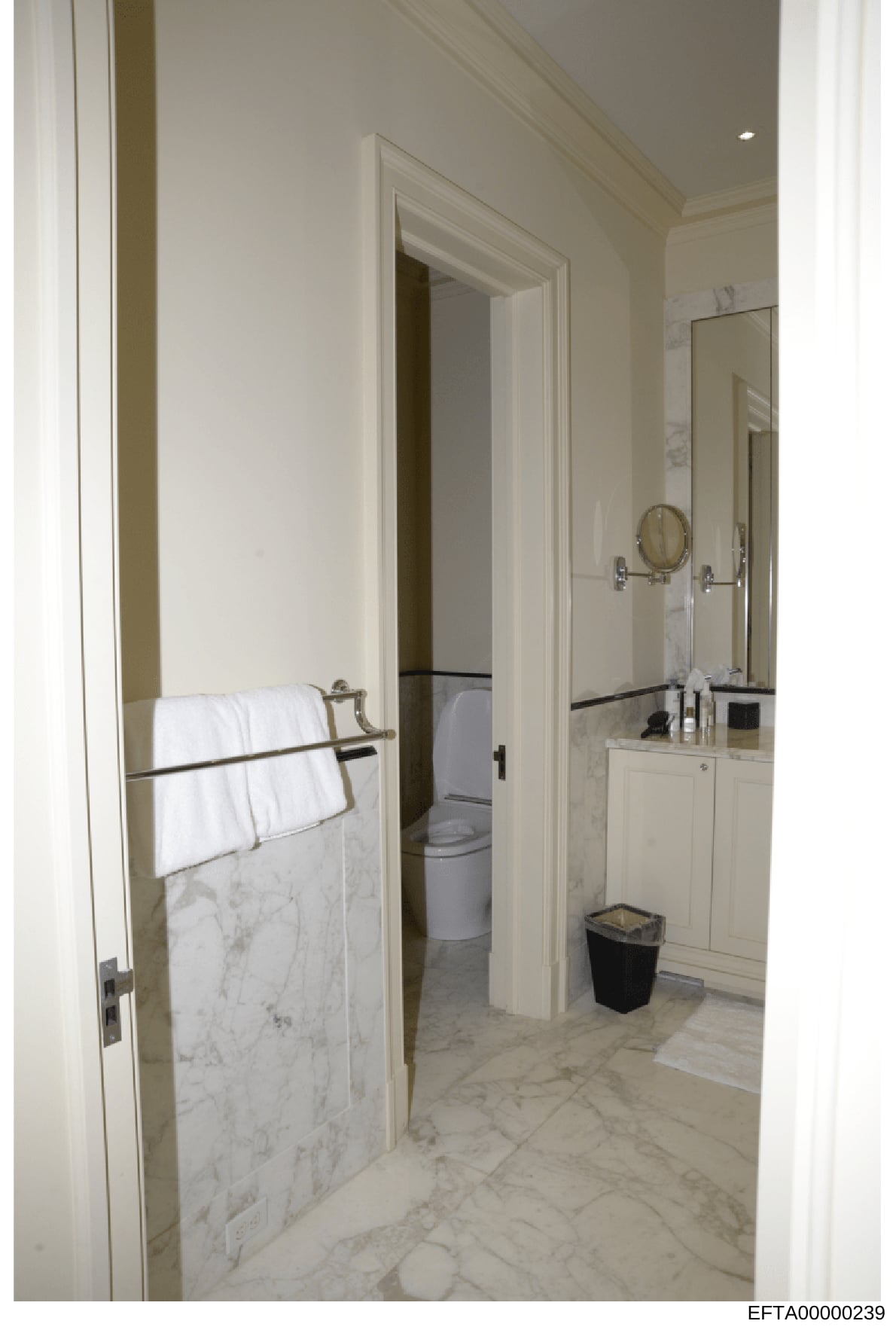 This is a photograph of a luxury bathroom interior, showing marble countertops, white cabinetry, and adjoining facilities. The image appears to be documentation of property interiors, likely from one of Jeffrey Epstein's residences as part of the inv