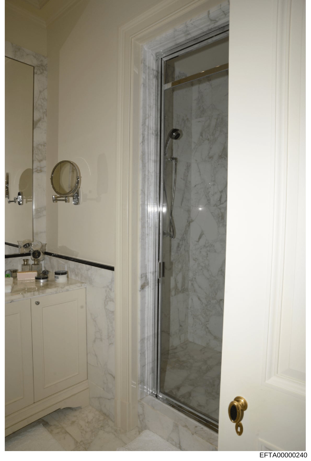 This photograph shows an interior view of an upscale bathroom featuring marble finishes, a walk-in shower enclosure with glass door, and a white vanity cabinet with countertop. The image is part of the Epstein investigation file documentation, likely