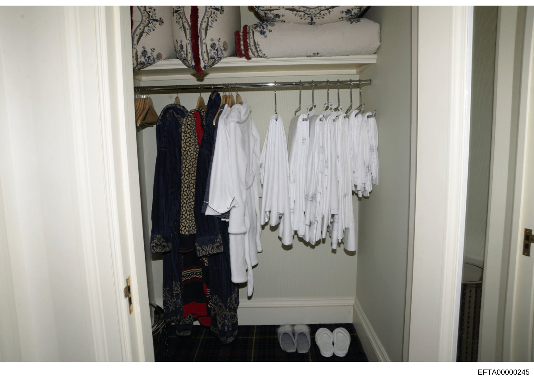 This photograph shows the interior of a closet or dressing room, displaying an organized collection of clothing including formal wear, white garments, and decorative items. The image appears to be evidence documentation from the Epstein investigation