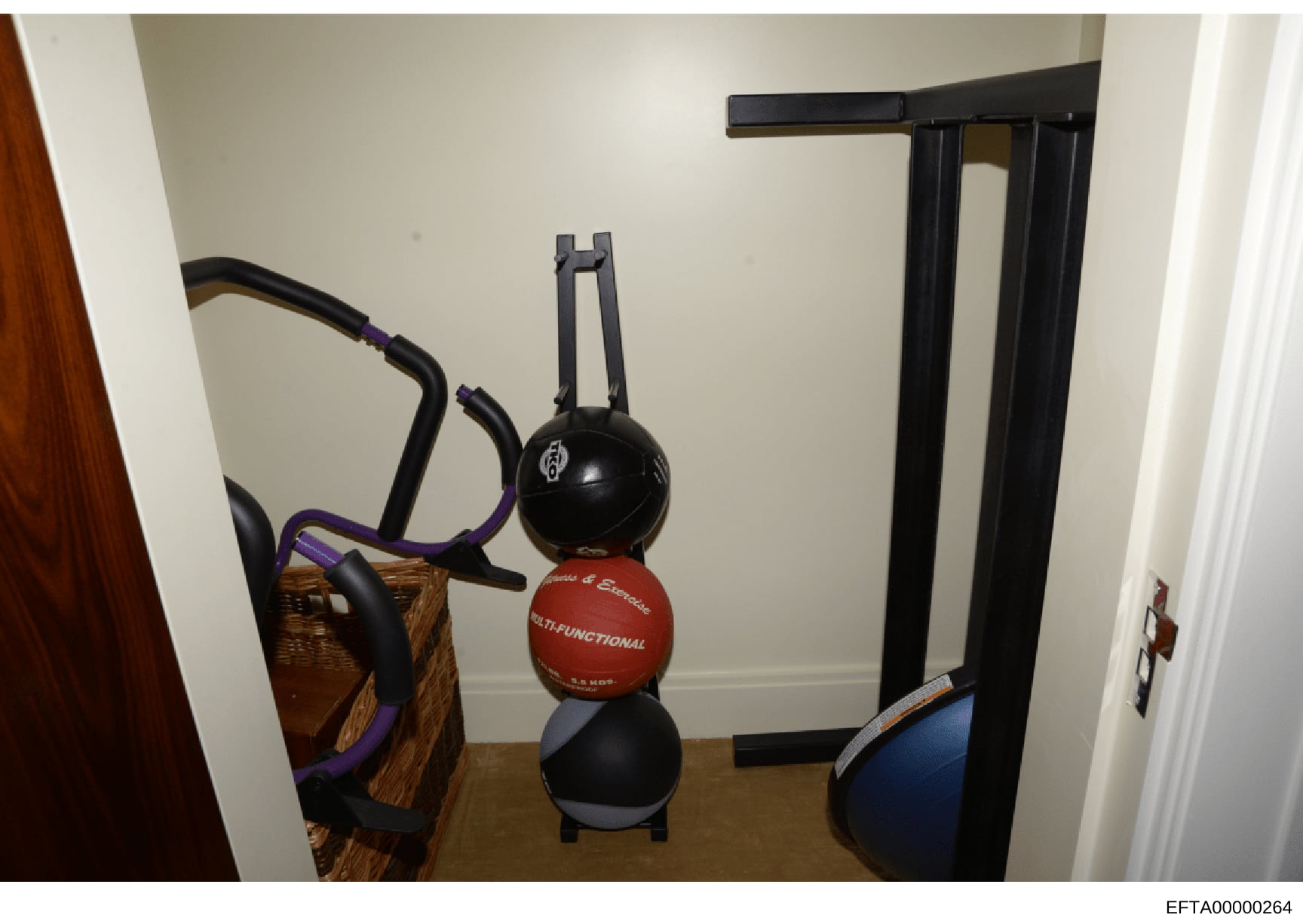 This photograph shows a small room or closet containing exercise and fitness equipment, including exercise bikes, medicine balls, and other gym apparatus. The image appears to be from an Epstein property and was documented as evidence during the inve