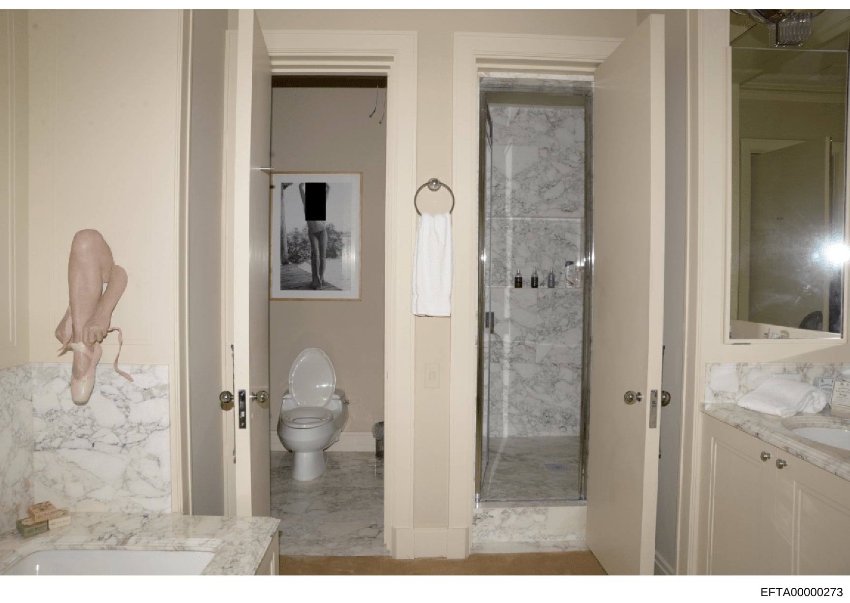 This photograph documents the interior of a luxury bathroom featuring marble countertops, vanities, a toilet, shower enclosure, and wall-mounted artwork. The image appears to be part of property documentation, possibly related to one of Epstein's res
