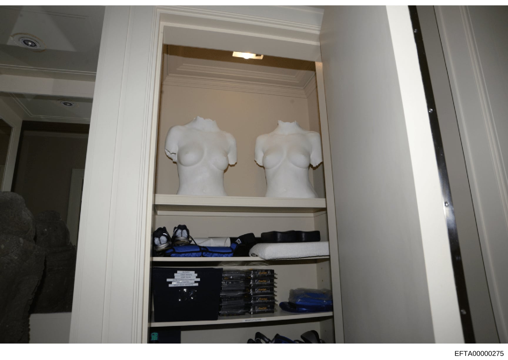 This is a photograph of an open closet interior, likely from one of Jeffrey Epstein's properties, showing white female mannequin torsos on the upper shelf, along with various personal items including shoes, clothing, and what appear to be DVDs or sim