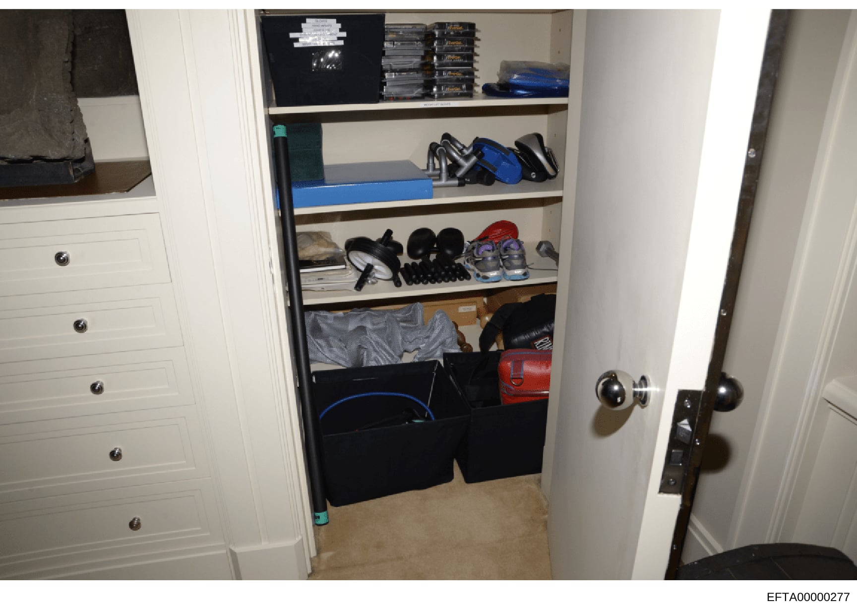 This is an evidence photograph showing the interior of a walk-in closet or storage space containing shelved items, clothing, shoes, bags, and miscellaneous personal belongings. The photo documents the contents of a residential storage area, likely ta
