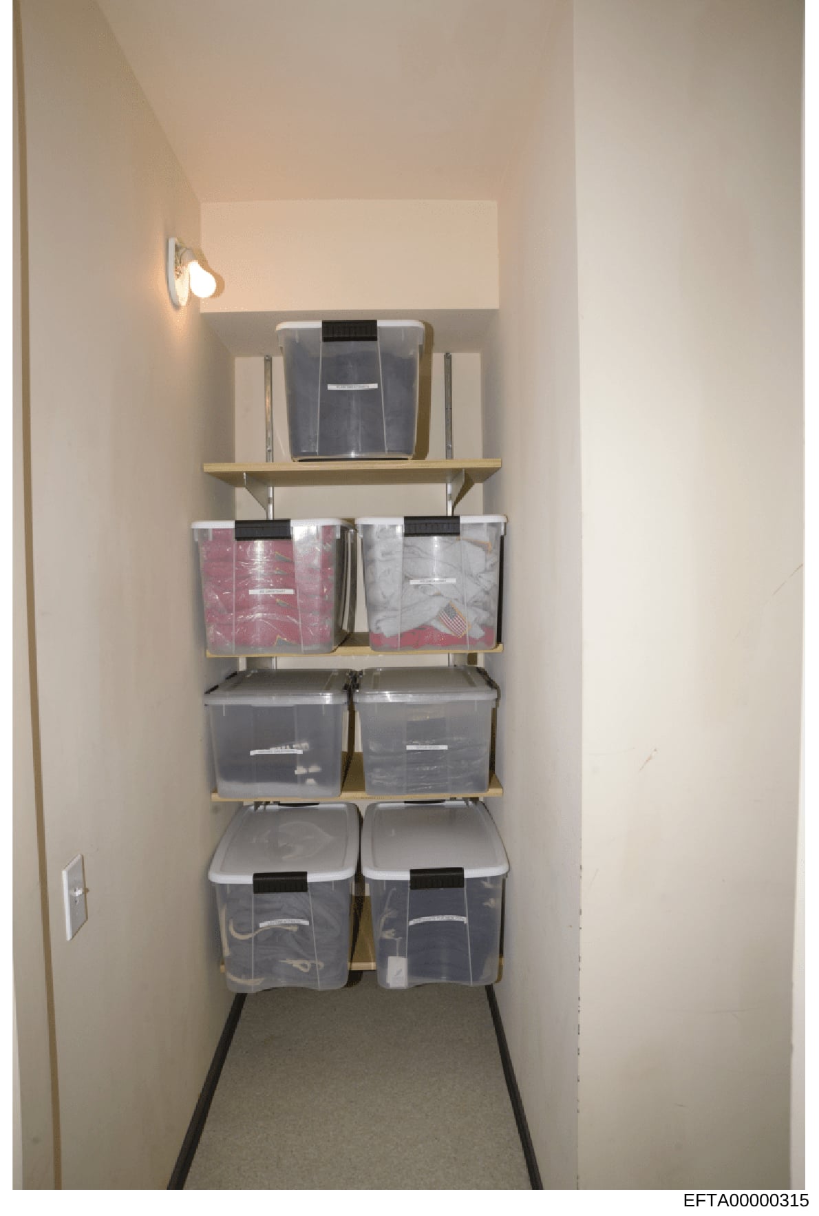 This is an evidence photograph documenting a residential storage closet containing organized plastic storage containers and boxes on wooden shelves. The closet appears to be part of a property search or inventory operation, with various sized clear a