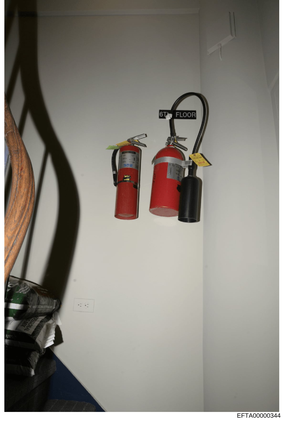 This photograph shows three fire extinguishers mounted on a white wall, labeled as being on the 6th floor. The image appears to be documentation of building safety equipment and interior conditions of a property under investigation. The presence of s