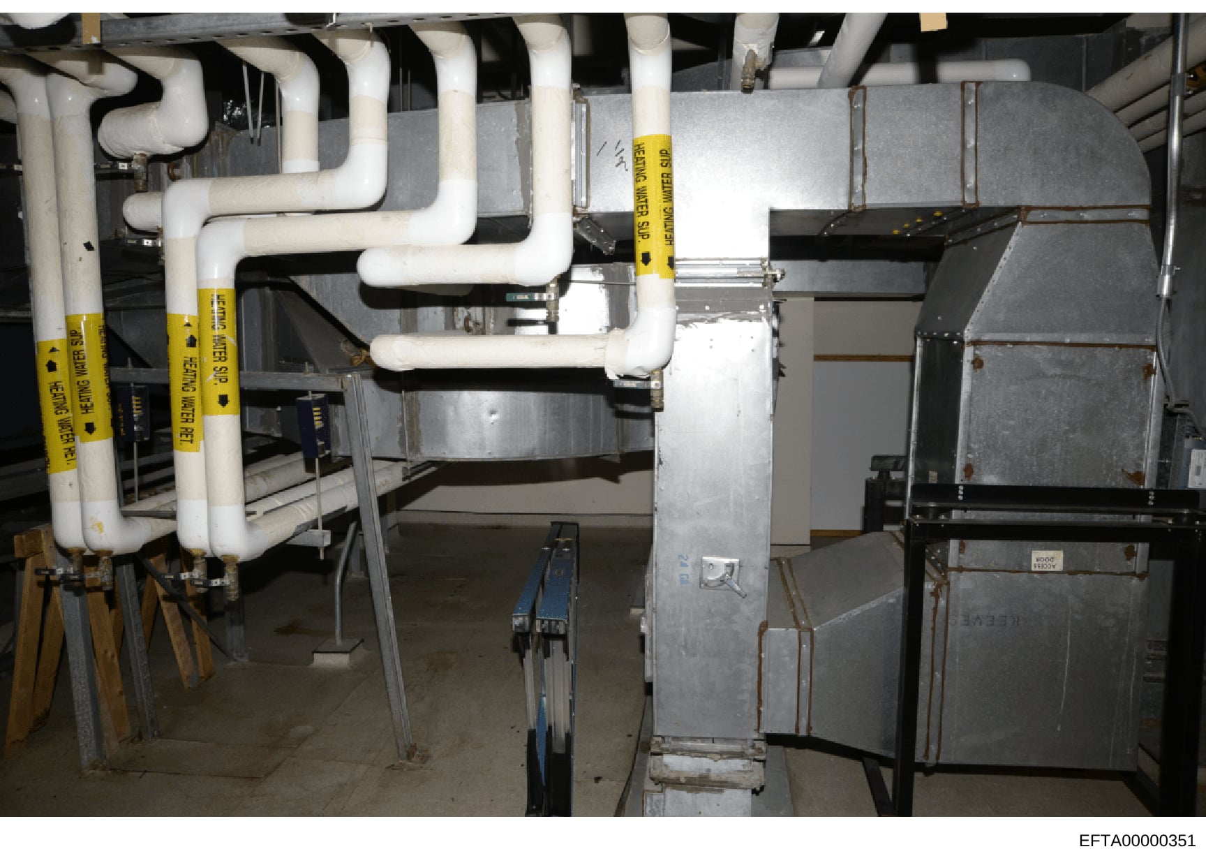 This is an evidence photograph showing HVAC piping, ductwork, and mechanical systems in what appears to be a basement or utility area of a property. Multiple white PVC pipes with yellow evidence tags are visible, suggesting this area was photographed