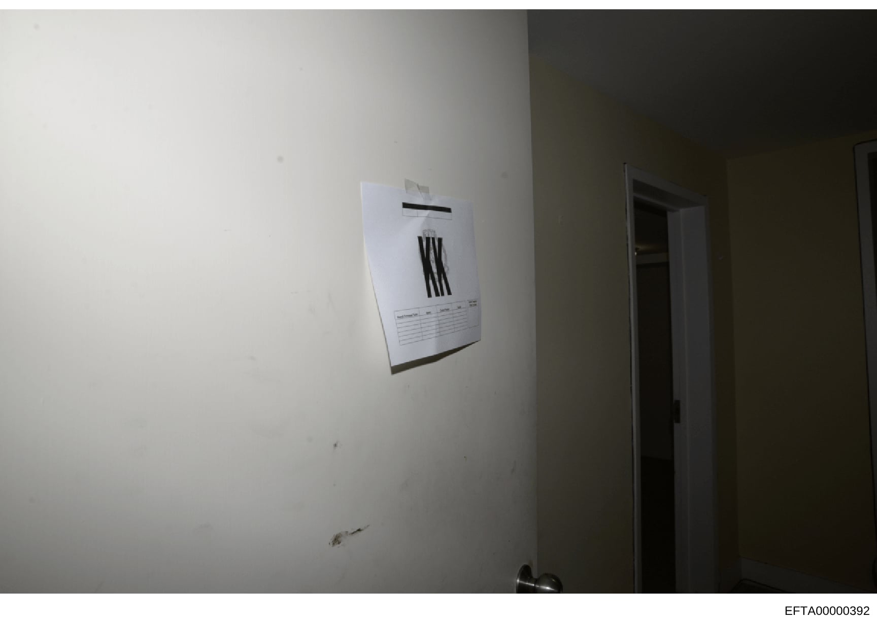 This is an evidence photograph showing the interior of a room with a wall-mounted thermostat unit and an adjacent doorway. The image appears to be part of a property documentation or forensic investigation record, with minimal markings or identifying