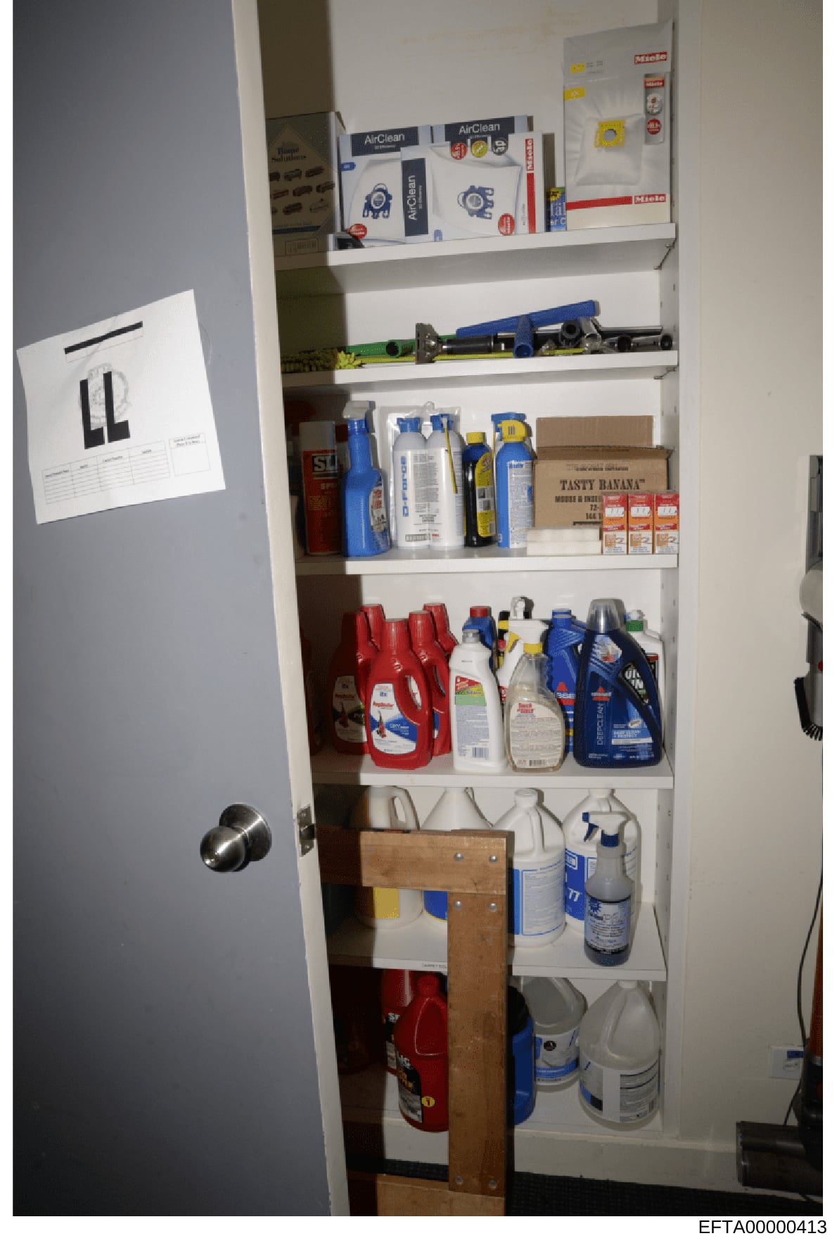 This photograph depicts the contents of a residential storage closet containing various household cleaning supplies, maintenance products, and tools. The closet is organized on multiple white shelves and contains items such as air filters, cleaning s