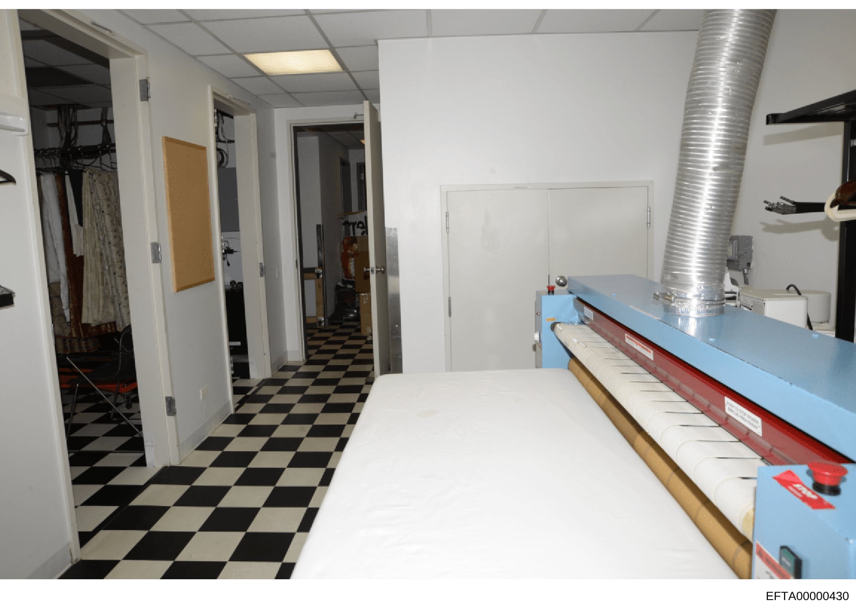 This is an evidence photograph showing an interior space with a black-and-white checkered floor, multiple doorways, storage areas, and what appears to be commercial or institutional equipment including a large blue counter or table on the right side.