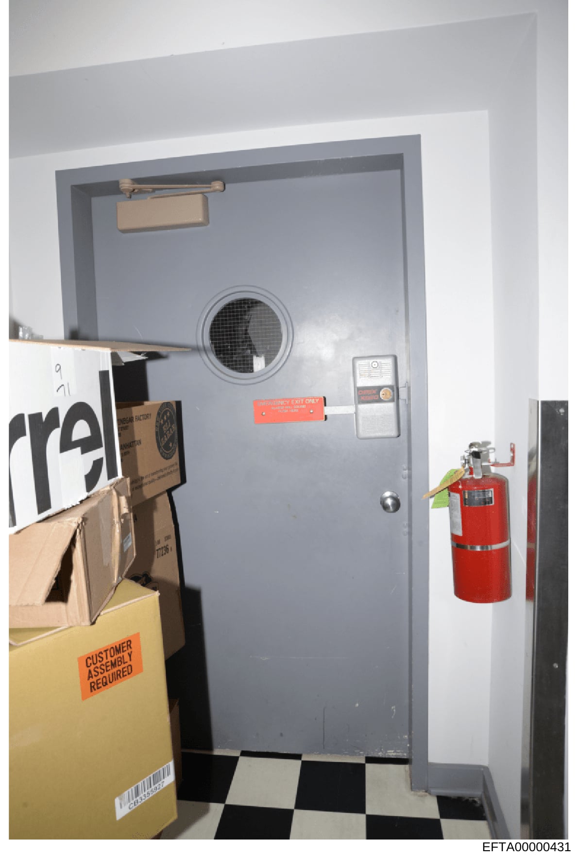 This is an evidence photograph showing a gray institutional door with security features, including a door closer, intercom system, and fire extinguisher. The door appears to be part of a secure facility or restricted area, with a black-and-white chec