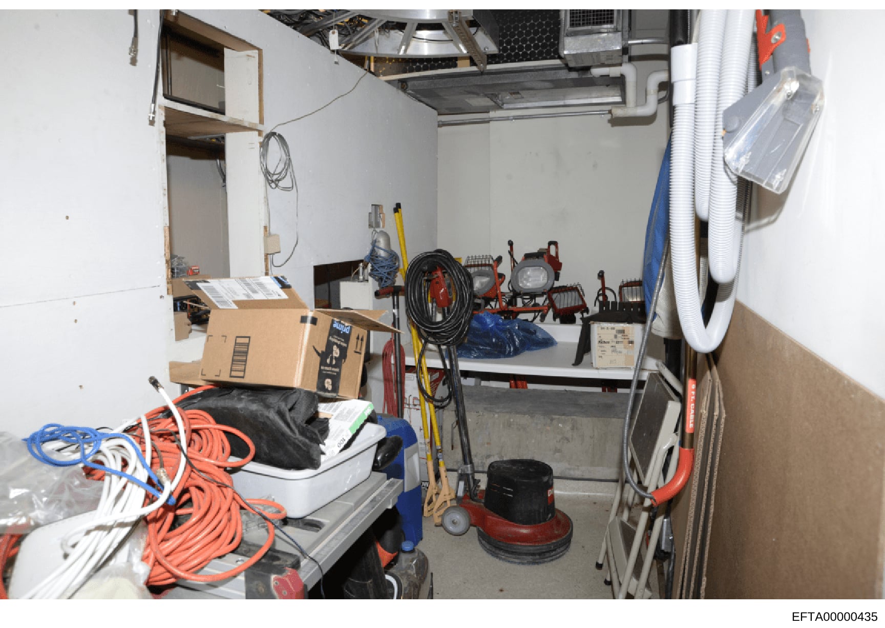 This is an evidence photograph showing the interior of a storage or utility room containing various maintenance and construction equipment, tools, and supplies. The image appears to be part of a property inventory or evidence documentation related to