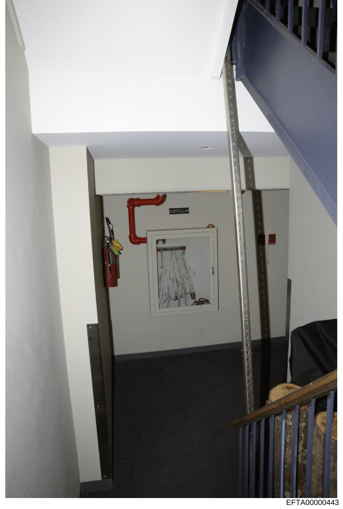 This is an evidence photograph showing an interior hallway or corridor in what appears to be a commercial or residential building. The image documents utility infrastructure including a red pipe labeled 'SUISCELLAR,' a fire extinguisher mounted on th