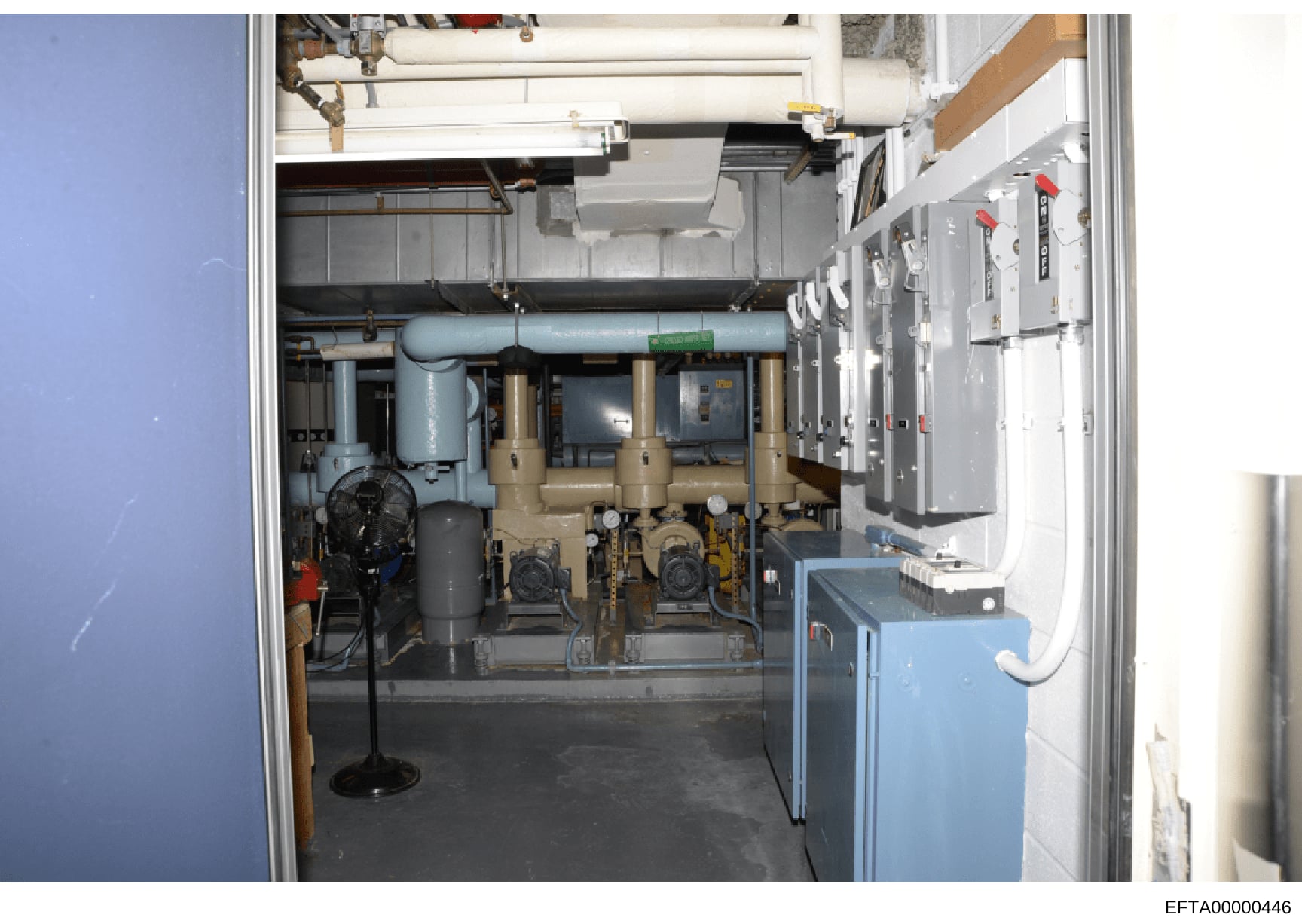 This is a photograph of a mechanical/utility room showing building infrastructure including HVAC equipment, pumps, piping systems, electrical panels, and other mechanical systems. The image appears to be from a property inspection or inventory docume