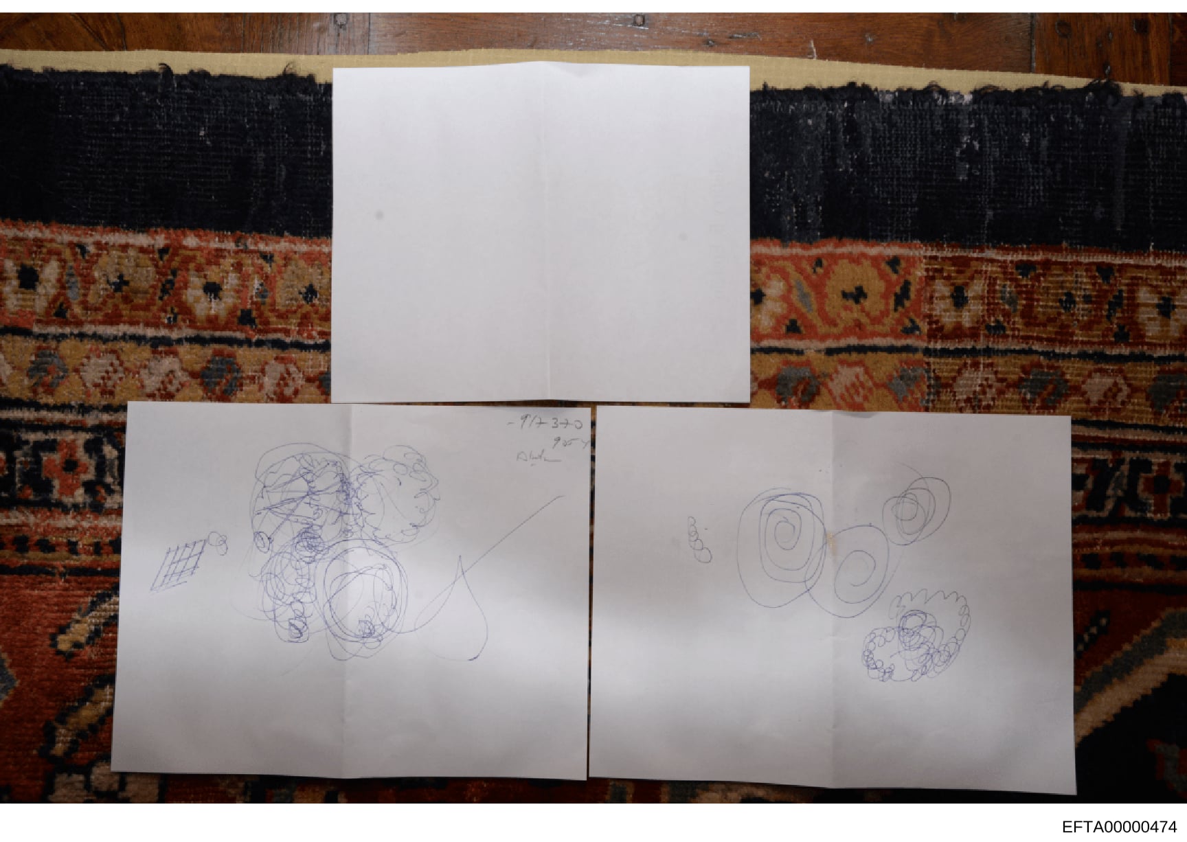 This photograph documents three sheets of white paper containing handwritten sketches and abstract drawings. The papers are photographed flat against a decorative rug with dark and rust-colored patterns. One sheet is dated 7/1/23 and contains various
