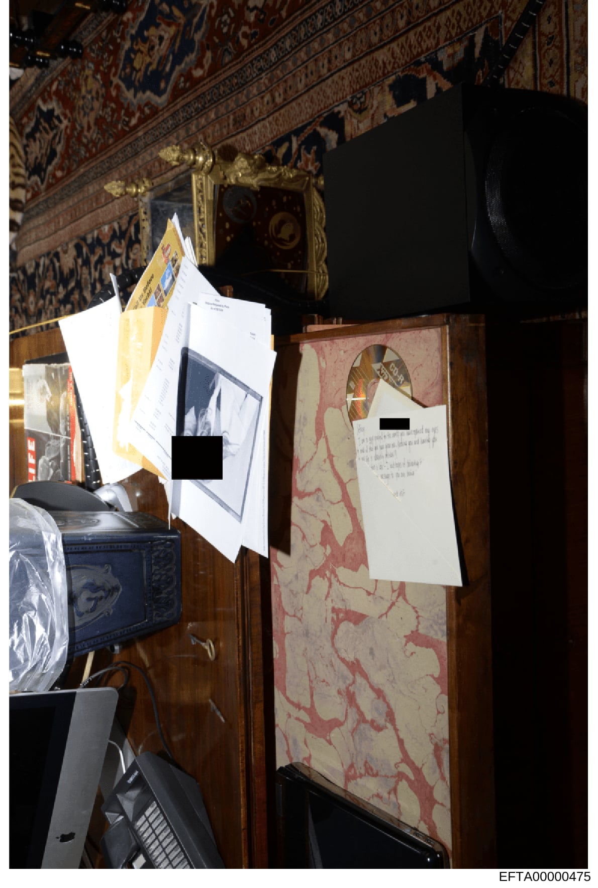 This is a photograph of an interior room showing luxurious décor including ornate ceiling with patterned panels, gilt-framed mirror, decorative furniture with red/cream patterned upholstery, and a blue ceramic piece. White documentation papers or evi