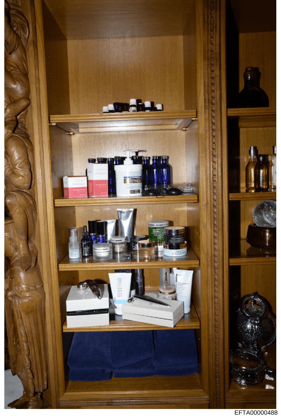 This photograph documents the contents of a wooden bathroom cabinet, showing multiple shelves stocked with various cosmetic, skincare, and personal care products including bottles, jars, and boxes. The image appears to be evidence documentation from
