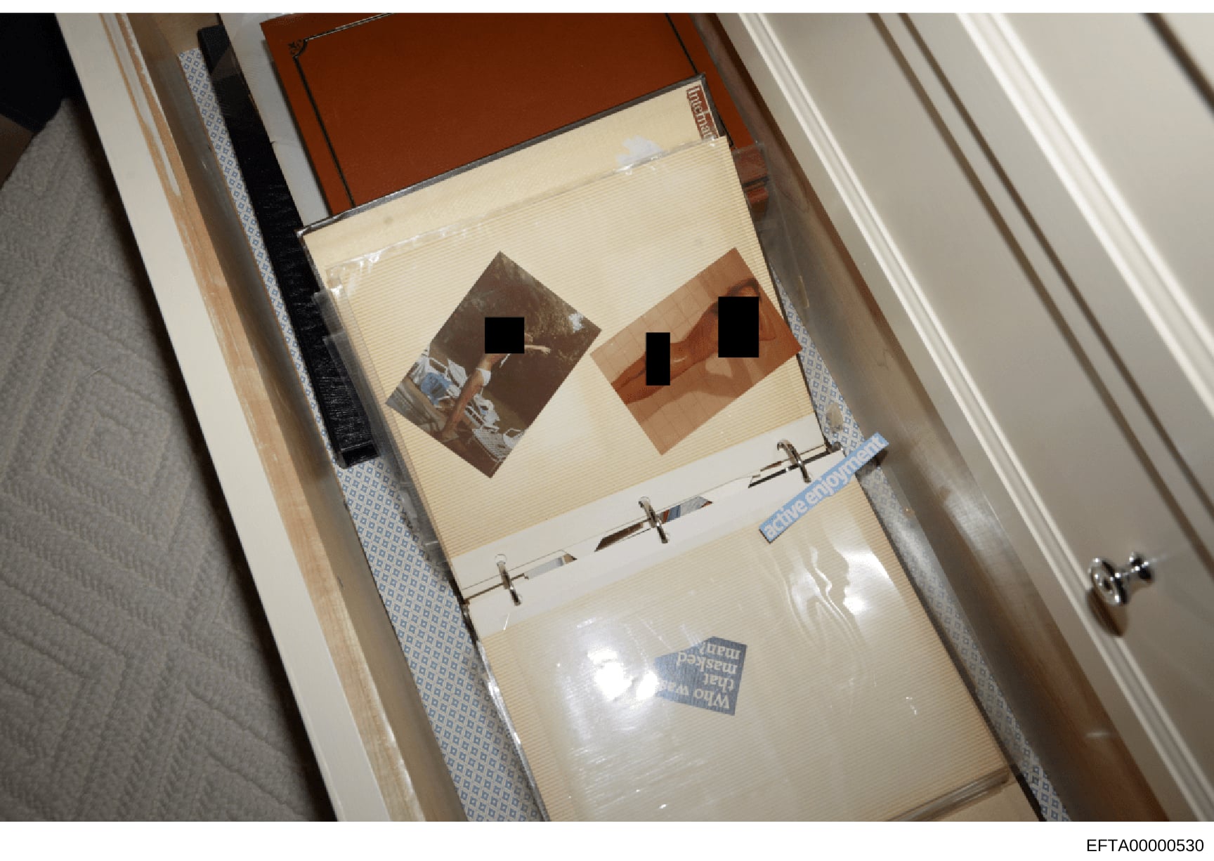 This photograph shows two interior room images mounted on a cream-colored board with faces redacted using black rectangles. The photos are stored in a wooden drawer lined with protective materials and labeled with evidence tape. This appears to be ev
