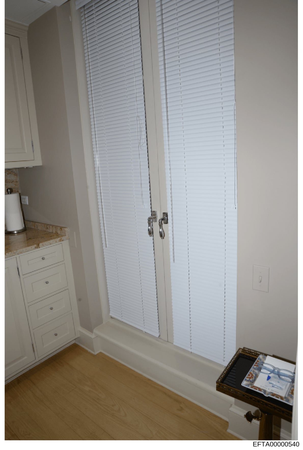 This is a photograph of a residential bedroom interior showing a closet with white louvered double doors, white cabinetry, and hardwood flooring. The image appears to be from property documentation or evidence photography related to an Epstein proper