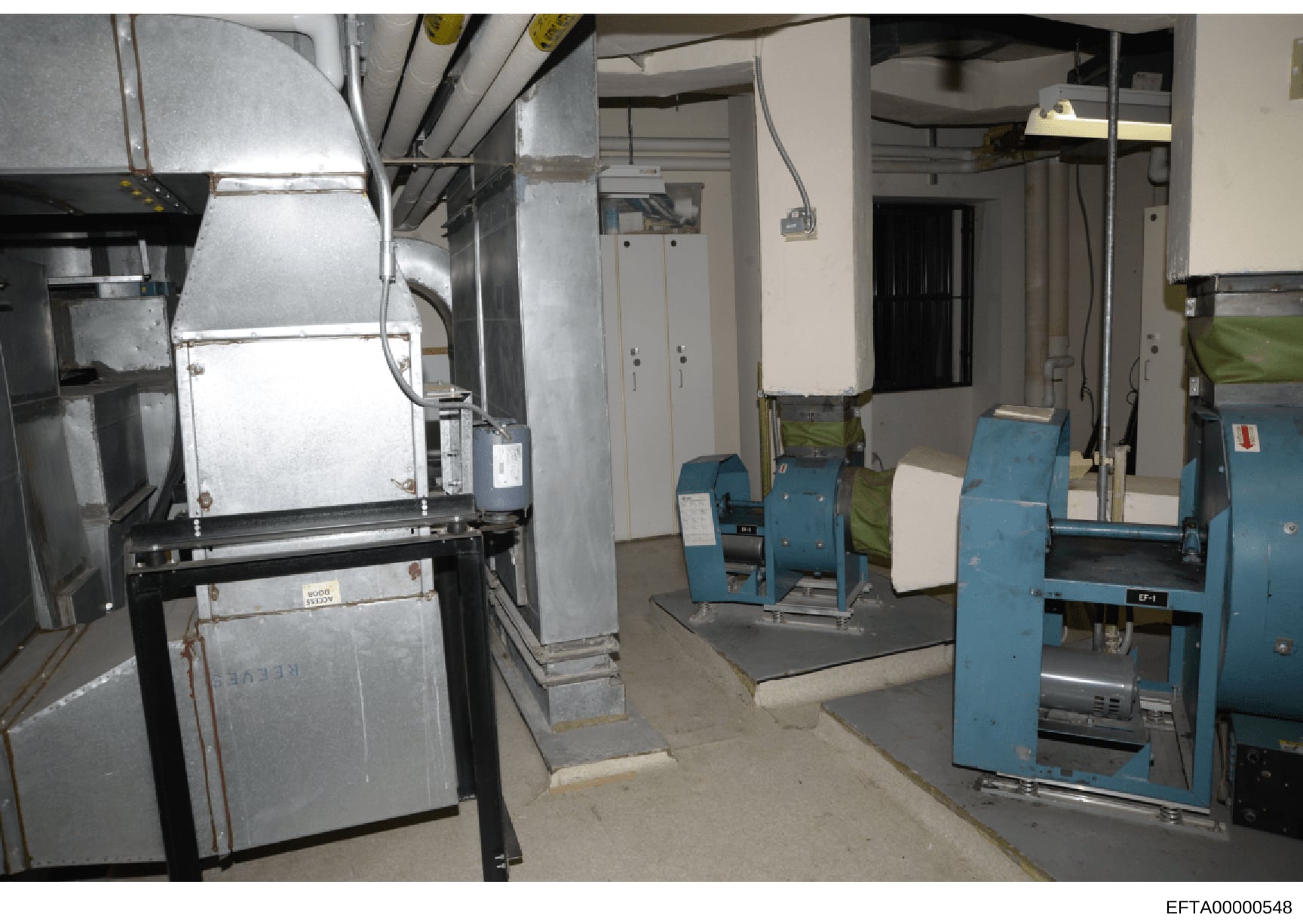 This is a photograph of an industrial or institutional basement/utility space containing large HVAC equipment, boilers, and other mechanical systems. The image appears to be evidence documentation from the investigation, showing the interior infrastr