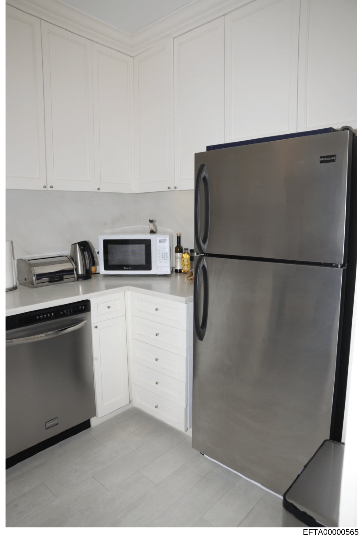 This is a photograph of a modern kitchen interior, showing appliances and cabinetry. The image appears to be evidence documentation from a property search or seizure, likely taken during the investigation to record the condition and contents of a res