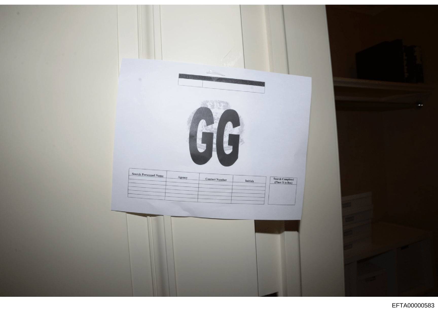 This is an evidence photograph showing a document or form affixed to a wall or surface, labeled with the initials 'GG' and containing a table with column headers for 'Search Personnel Name,' 'Agency,' 'Contact Number,' 'Initials,' and 'Search Complet