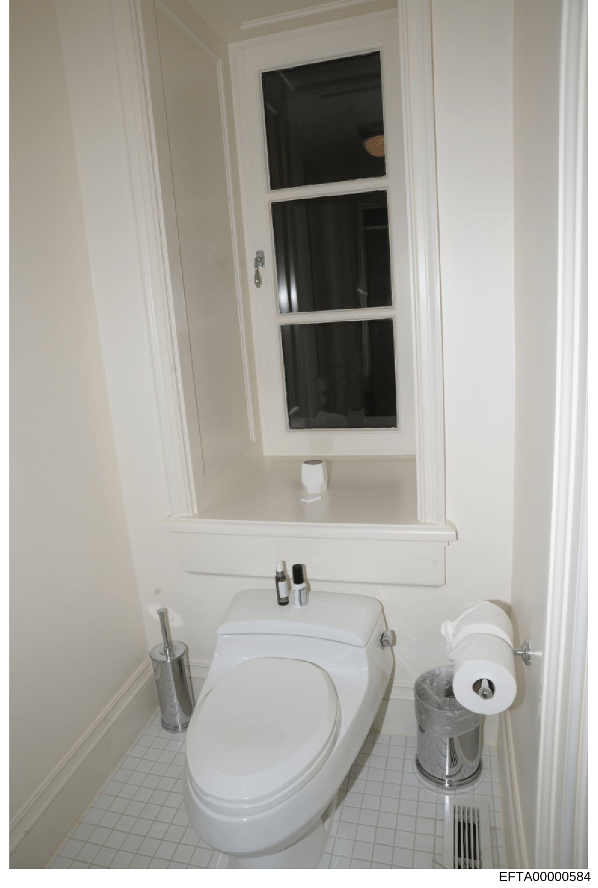 This is a photograph of a residential bathroom interior, showing a white toilet, pedestal sink, medicine cabinet with mirror, and basic bathroom accessories. The image appears to be documentation of a property's interior, likely taken as part of the