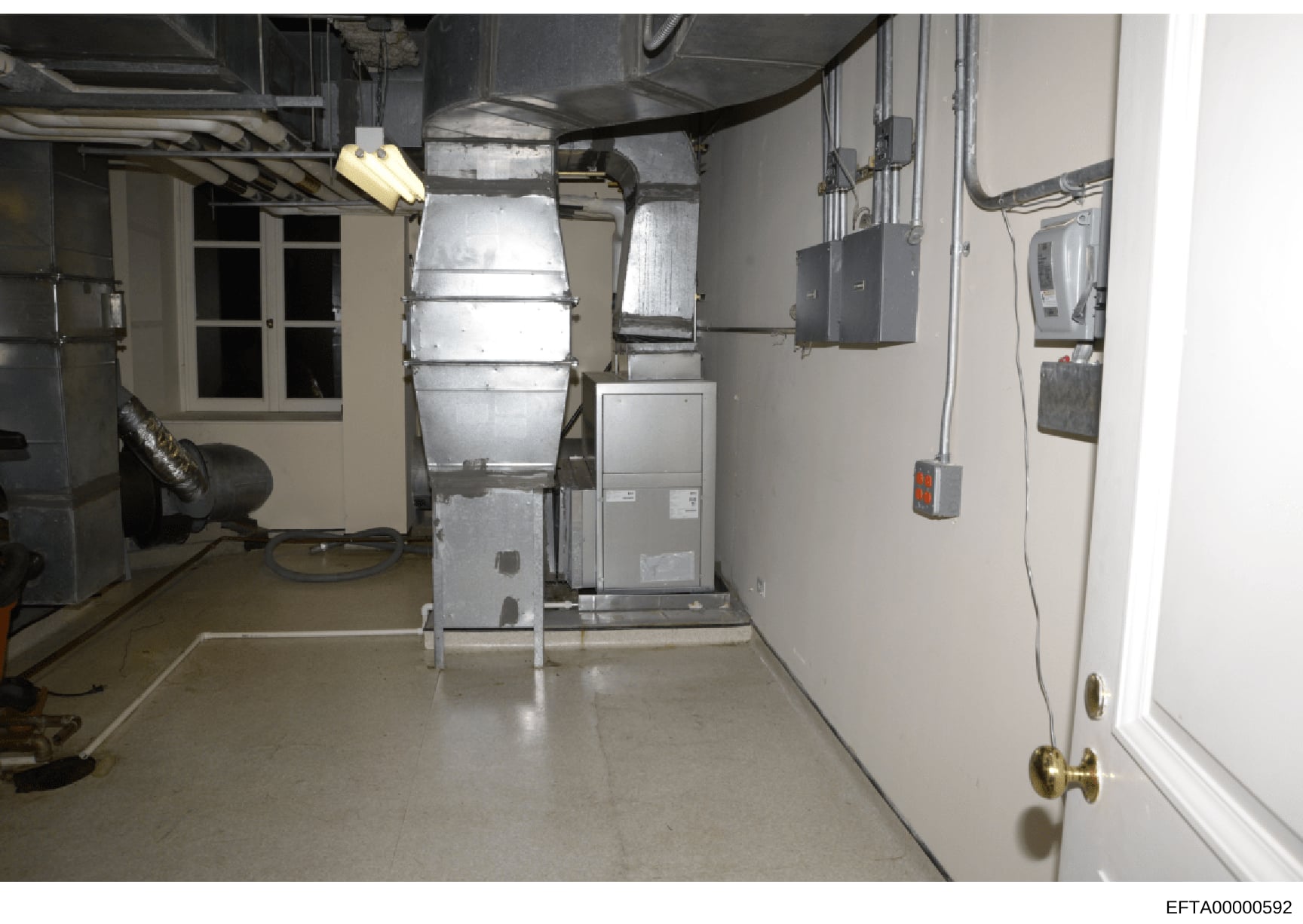 This photograph shows a basement mechanical room containing heating, ventilation, and air conditioning (HVAC) equipment, electrical panels, and utility infrastructure. The image captures the infrastructure of a residential property, likely from one o