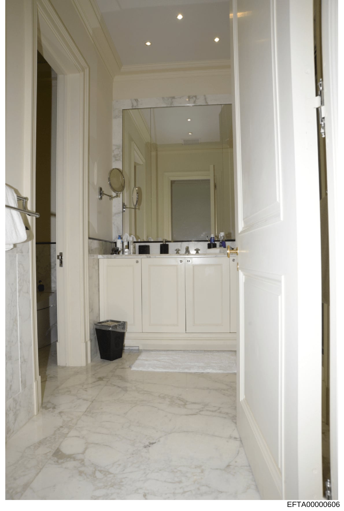 This is a photograph of an upscale bathroom interior, likely from one of Jeffrey Epstein's properties. The image shows a spacious, elegantly designed bathroom with high-end finishes including marble flooring, a large mirror, white cabinetry, and rece