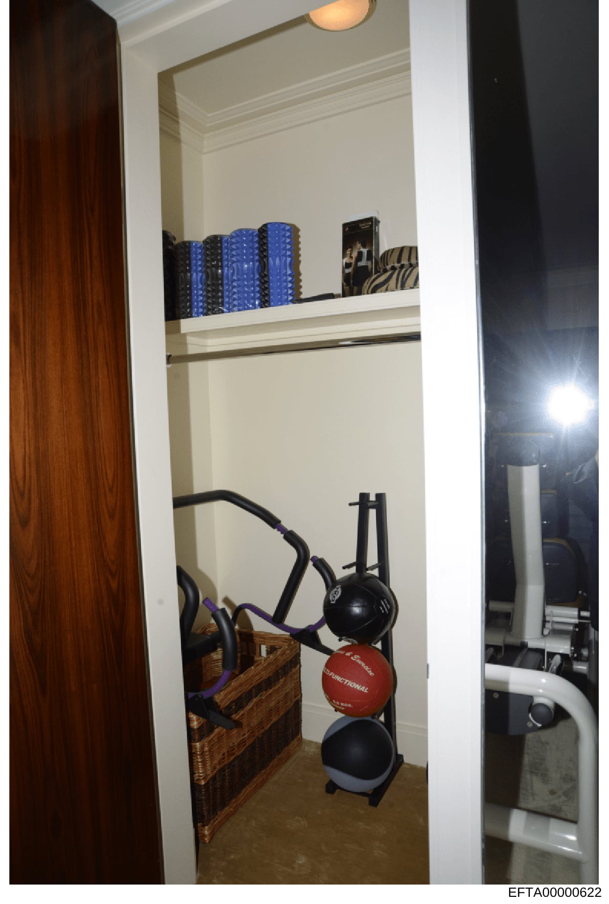 This photograph shows a closet or storage area containing exercise equipment, including medicine balls, resistance bands, and hair styling tools. The image appears to be documentation of a residential property's interior, likely from an evidence or p