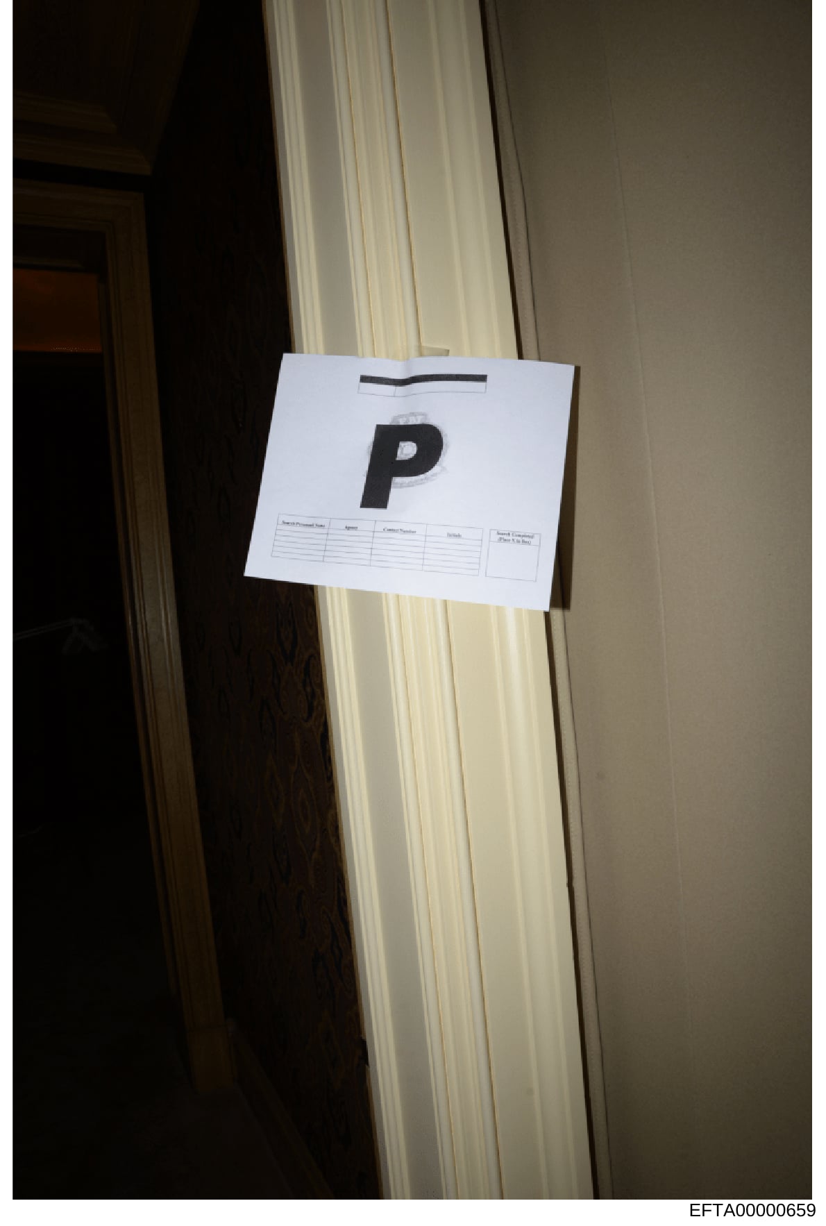 This is a photograph of a white document package or evidence envelope marked with the letter 'P' affixed to a door frame. The package appears to contain forms or documentation with blank fields visible. The photo shows the item in situ as part of the