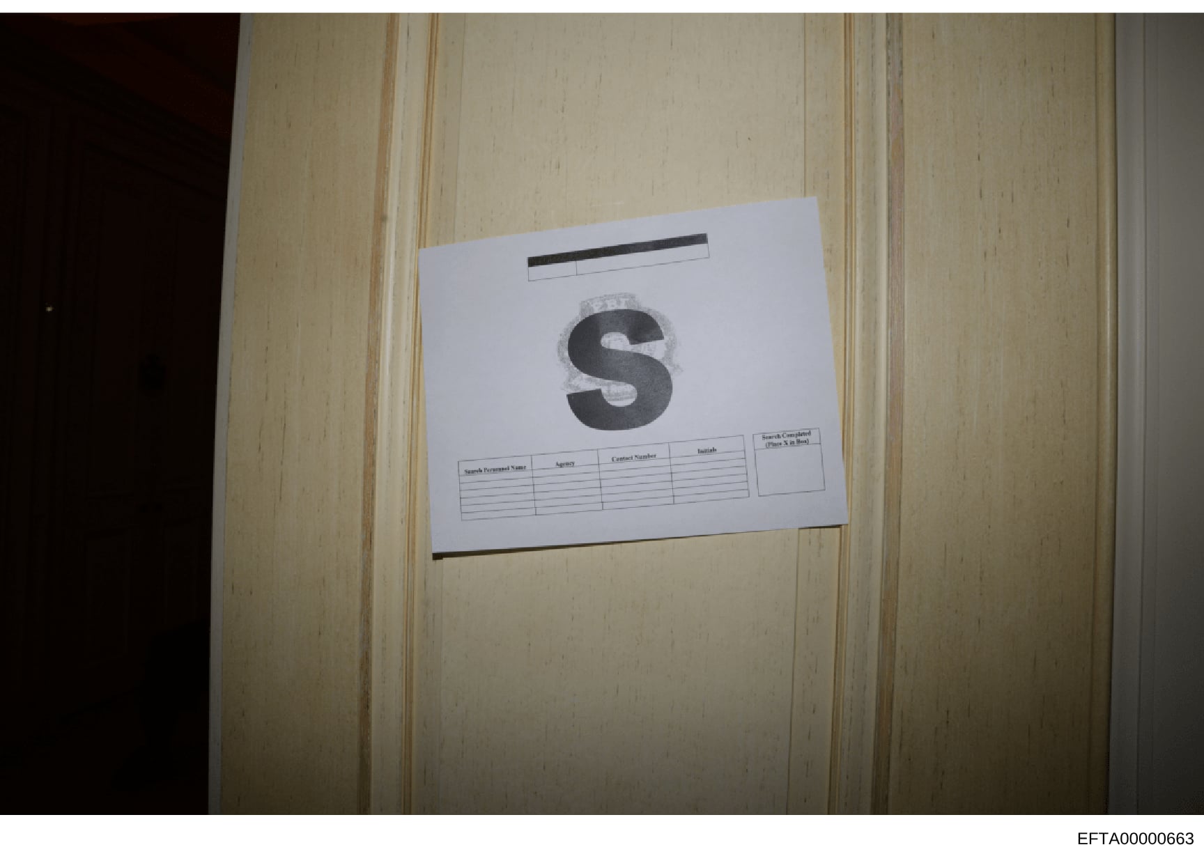 This is a photograph of a white document folder or evidence container labeled with a large letter 'S' and what appears to be a search warrant information form. The label includes fields for search warrant number, agent, contact number, and initials.
