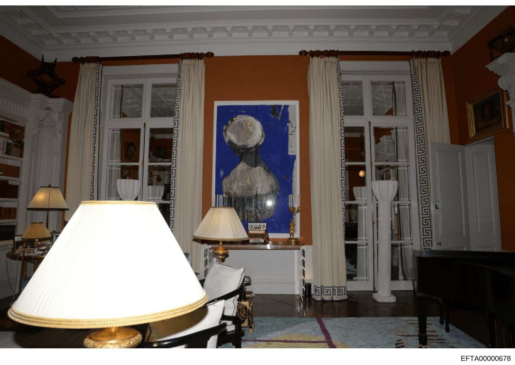 This is a photograph of a formal interior room, likely from one of Epstein's properties, showing an elegantly decorated space with ochre-colored walls, classical architectural details, period furniture, and contemporary artwork. The image documents t
