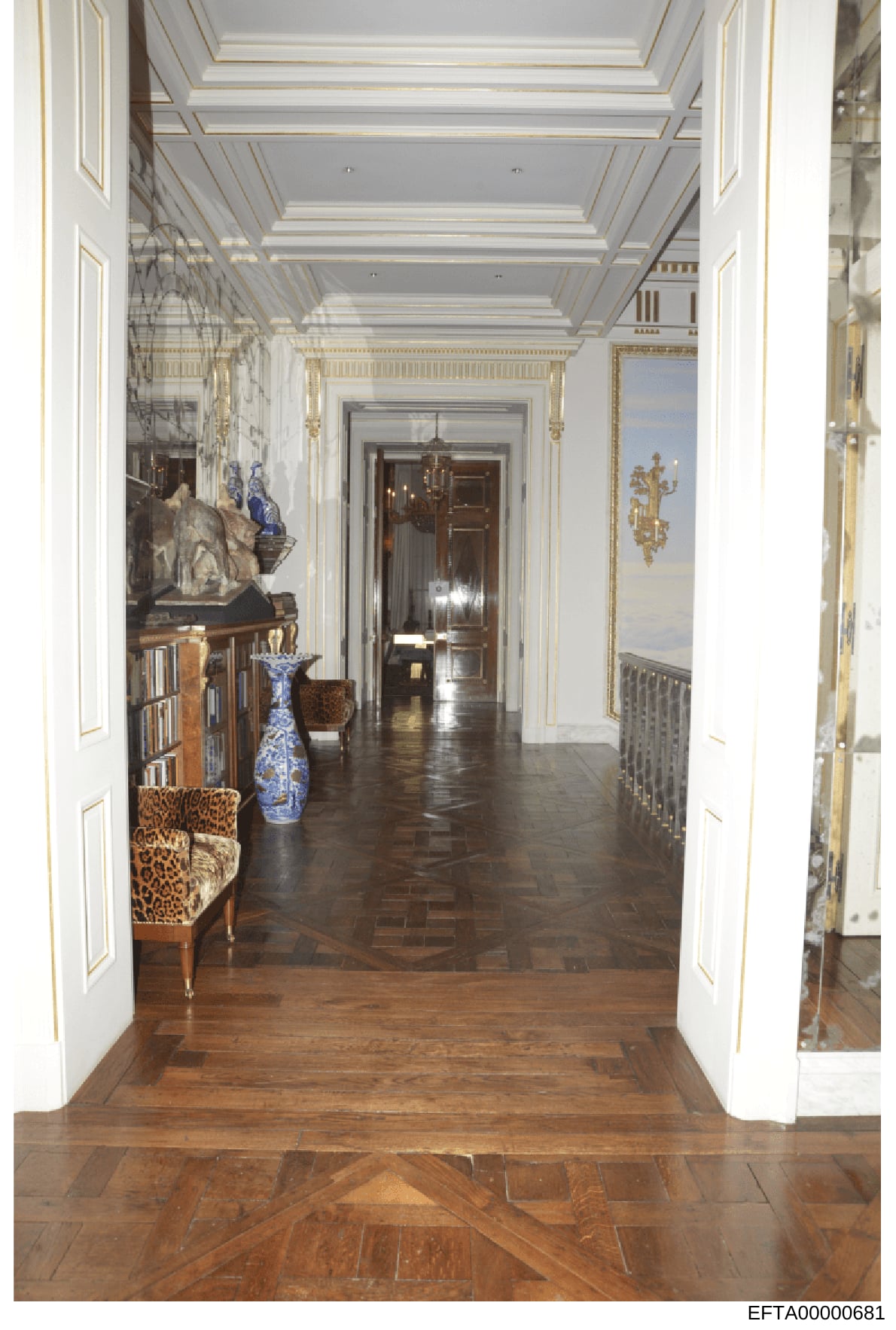 This is a photograph of an elegant hallway in one of Jeffrey Epstein's properties, showing the interior design and luxury furnishings. The image displays ornate architectural details, high ceilings with decorative molding, fine art, and antique furni