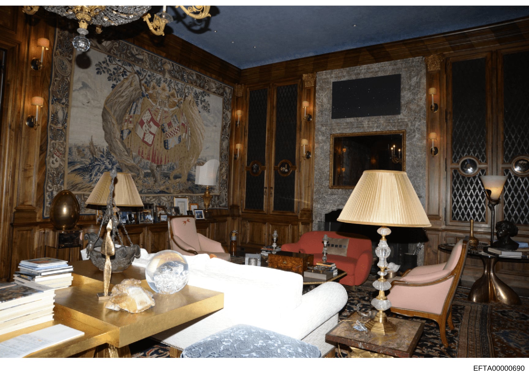This photograph documents an elegantly appointed interior room featuring high-end furnishings, artwork, and decorative objects. The space contains period furniture, ornate wall tapestries, crystal lighting fixtures, and collectible items arranged thr