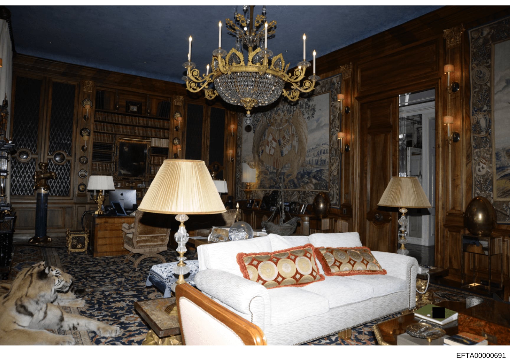 This photograph depicts an opulently decorated bedroom featuring high-end furnishings, including a crystal chandelier, wood paneling, fine art, and luxury bedding. The room appears to be part of a mansion or elite property, consistent with residences