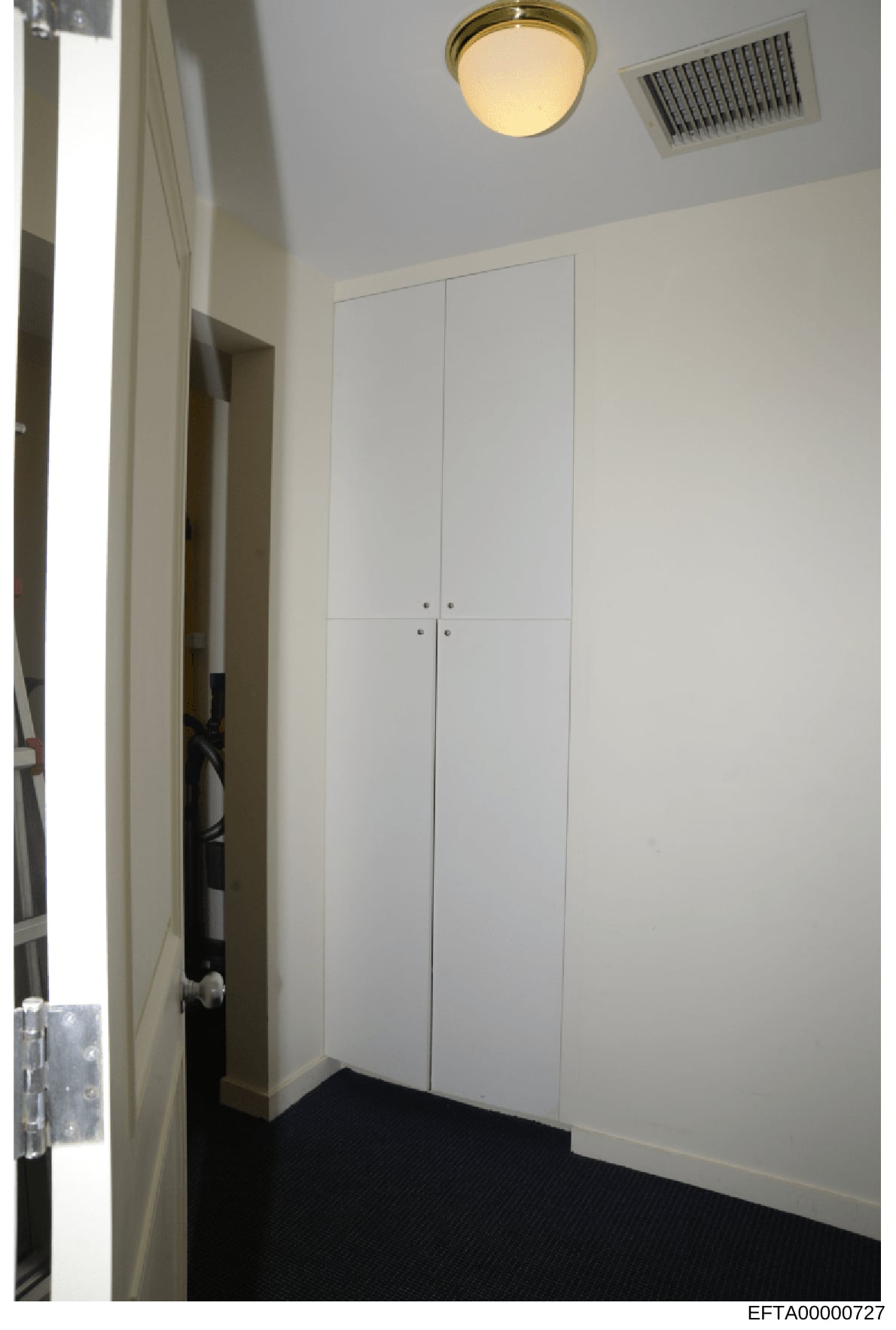 This is an evidence photograph showing the interior of a closet or small storage room with white built-in cabinetry. The image captures the room's layout, fixtures, and finishes as part of the investigation's documentation of properties associated wi